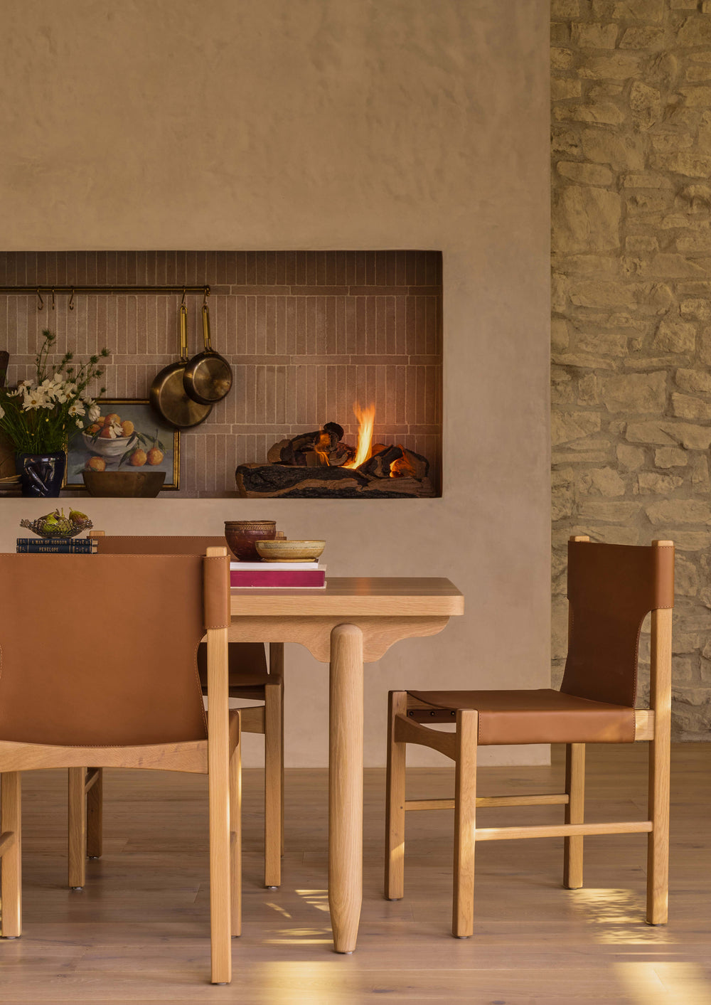 A set of Henrik Dining Chairs arranged around a white oak dining table beside a fireplace. The warm leather upholstery and natural wood tones bring comfort, texture, and sophistication to the space.