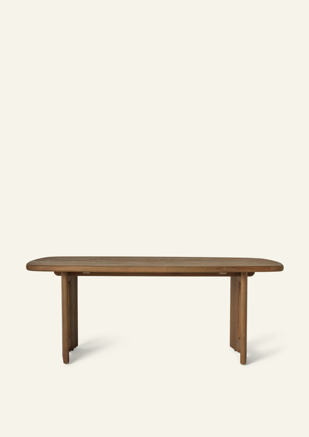 Front view of the reclaimed teak dining table showcasing its rounded rectangular slatted top and symmetrical pedestal base design. The substantial construction balances visual weight with an approachable silhouette.