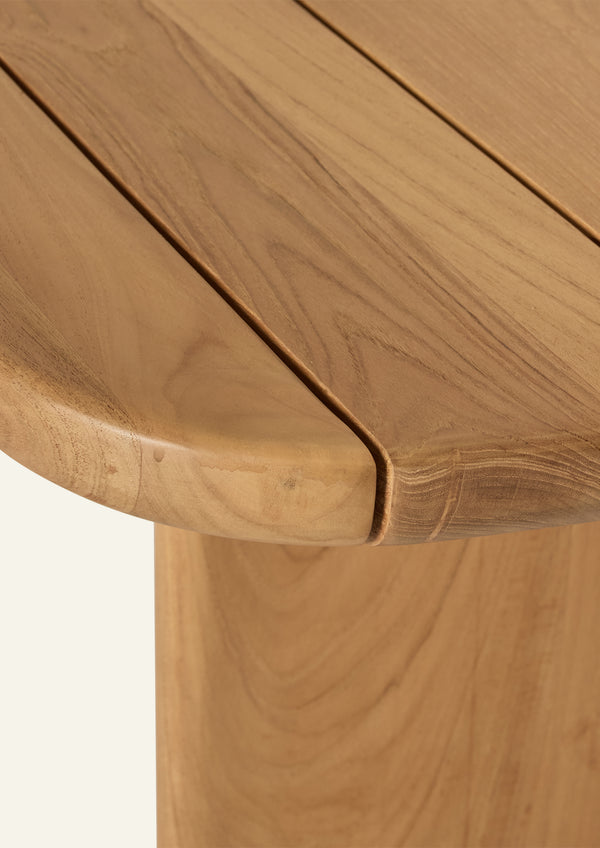 Close-up of the teak tabletop highlighting the rounded edge profile, slatted construction, and natural wood grain variation. The smooth finish showcases the material’s rich tone and organic character.