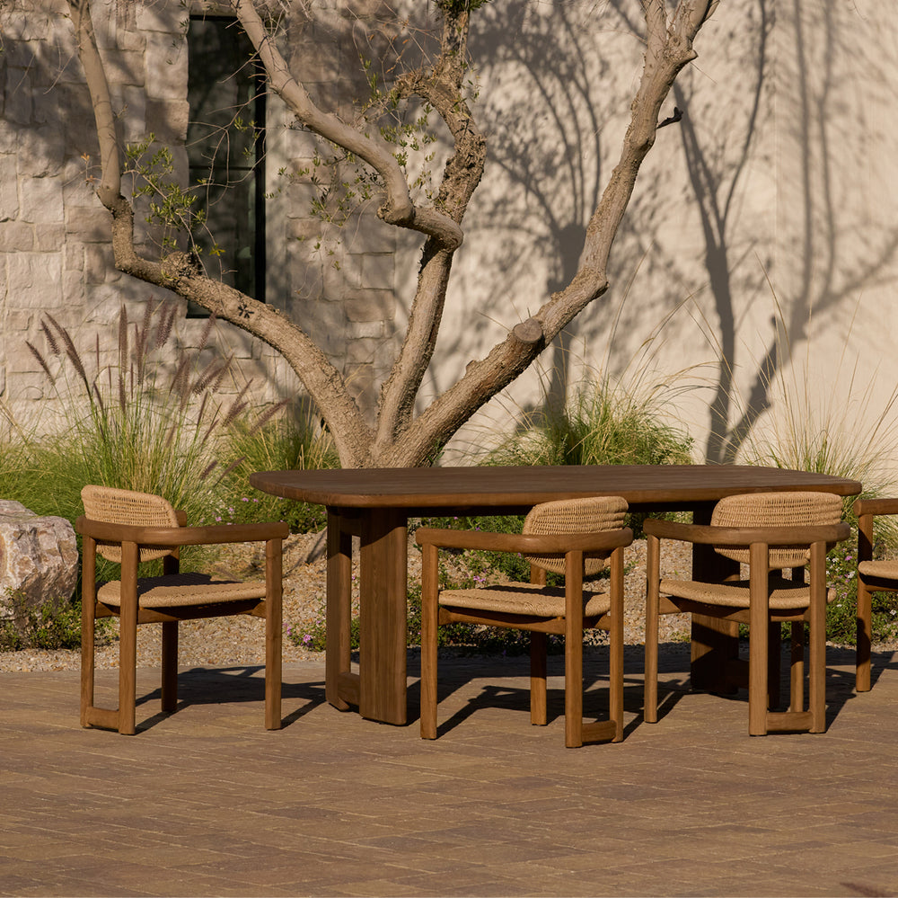 Dark teak outdoor dining set with Hollis dining table and Vera chairs on a stone patio. 
