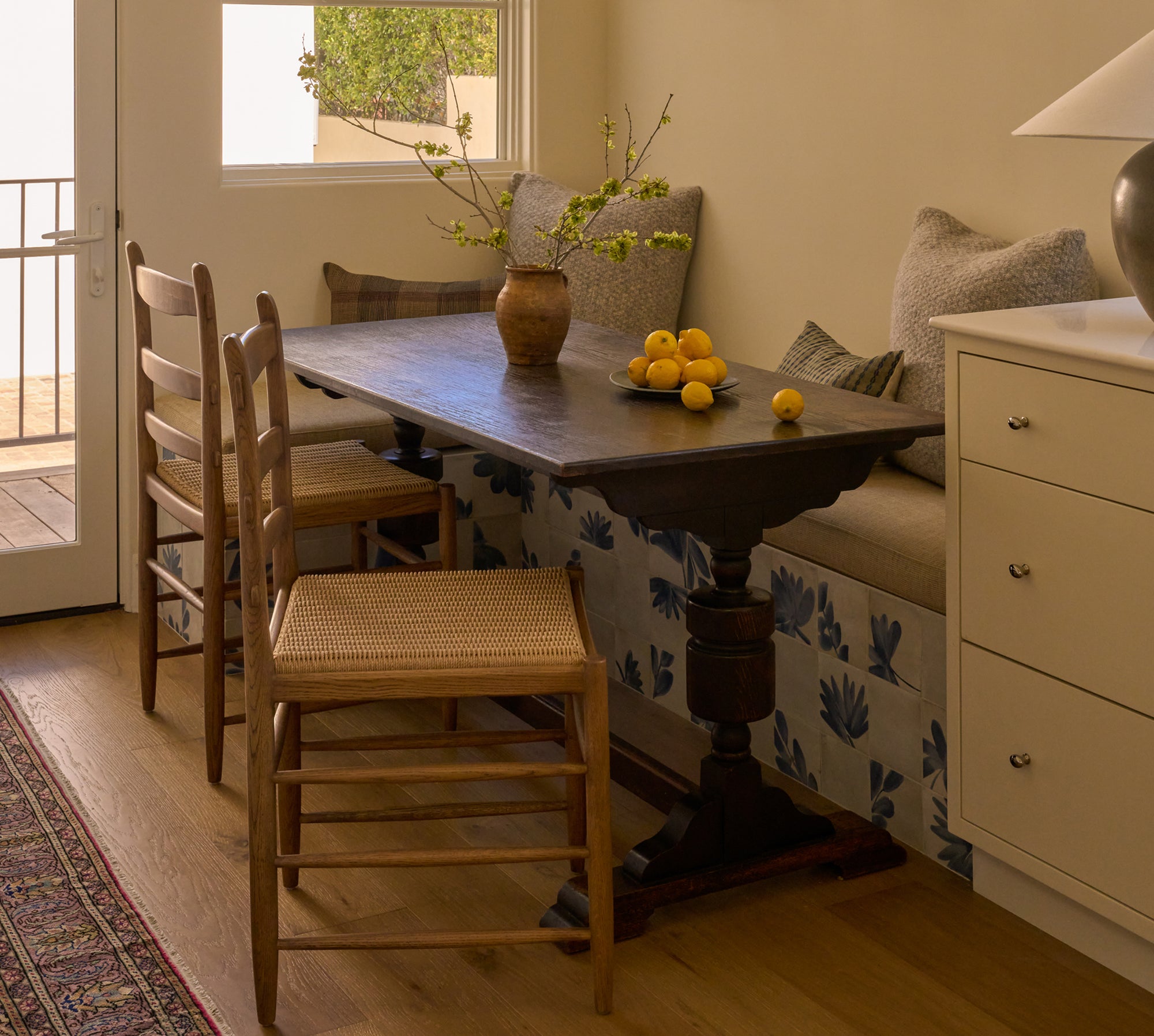 Modern breakfast nook area with vintage wooden table, Tiga honey oak dining chairs, and a built-in bench against a wall.