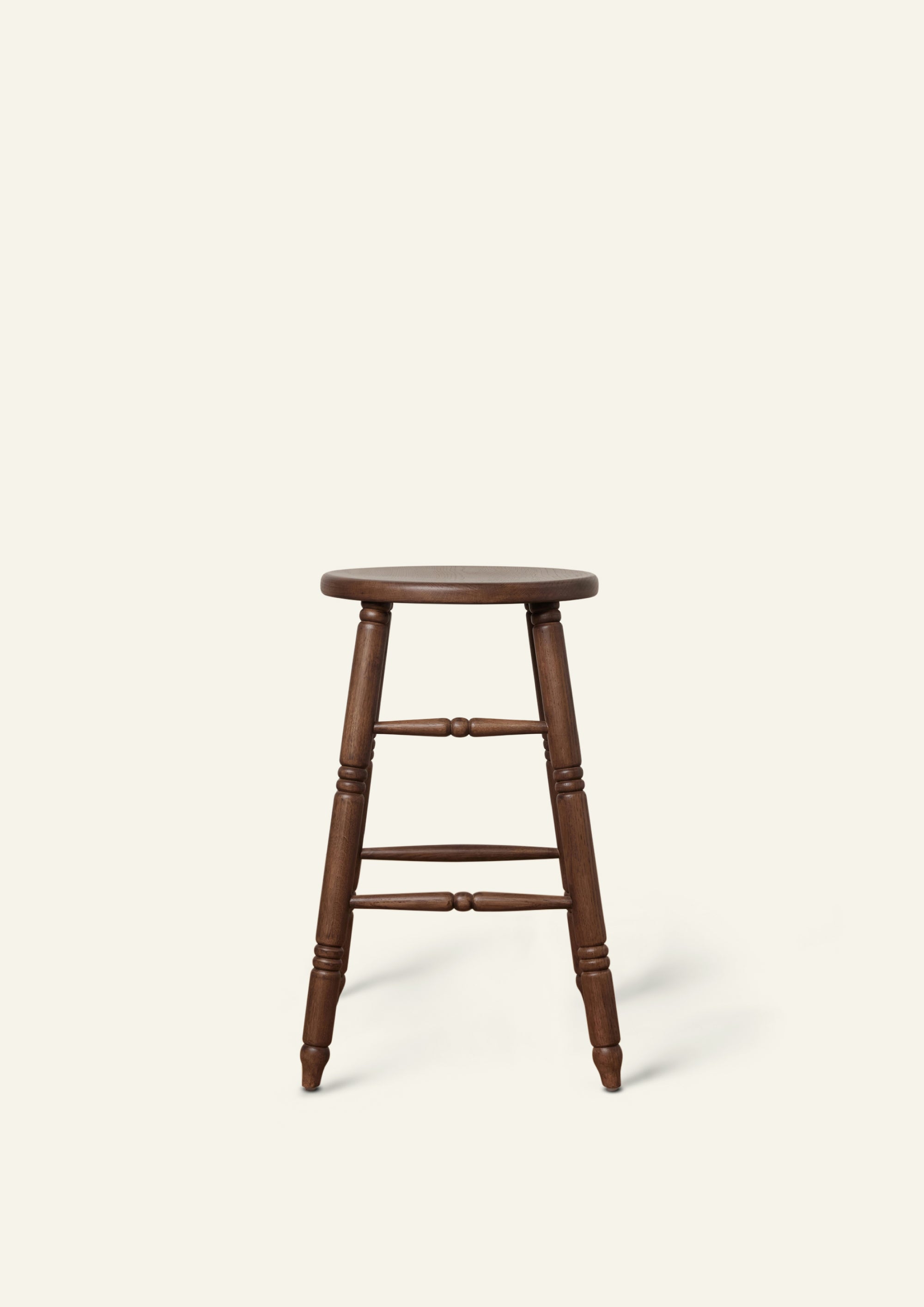 Side view of a classic counter stool crafted from solid brown oak. Hand-turned legs and stretchers lend traditional character, while the dark wood finish gives the piece a warm, refined presence.