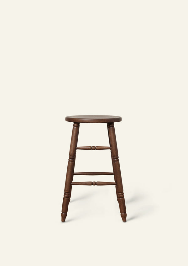 Side view of a classic counter stool crafted from solid brown oak. Hand-turned legs and stretchers lend traditional character, while the dark wood finish gives the piece a warm, refined presence.