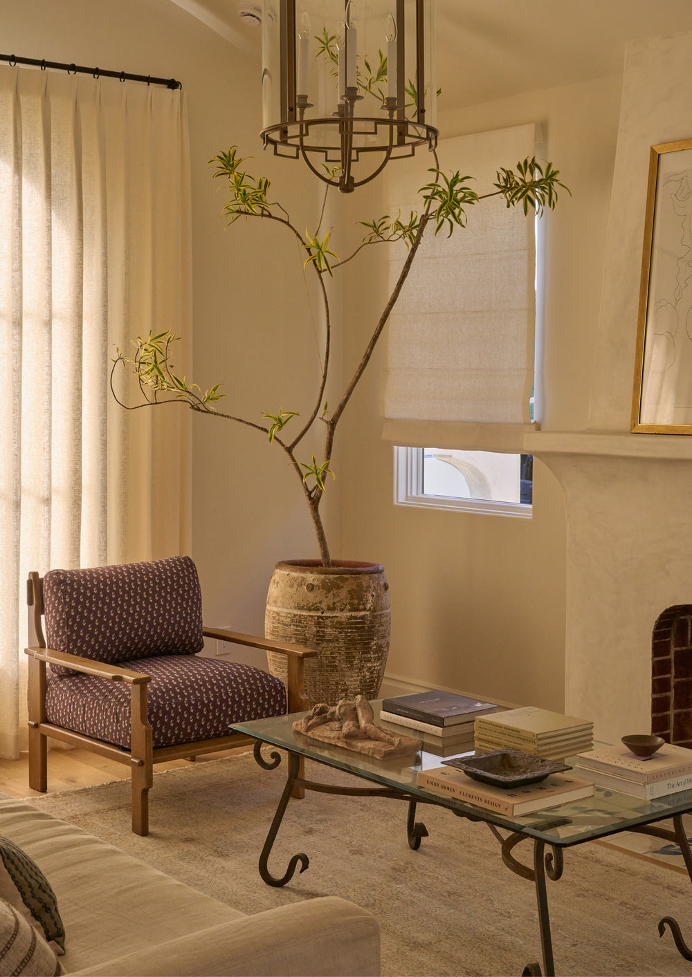 Brown floral lounge chair styled in a warm, collected living room beside a coffee table and large ceramic planter. The patterned upholstery adds subtle color and texture to the inviting space.