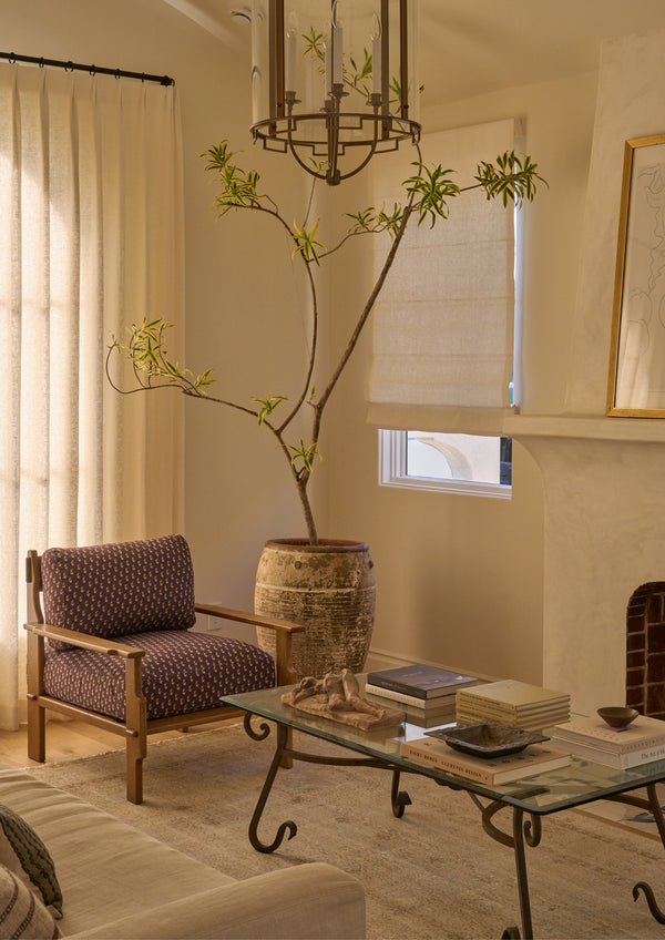 Brown floral lounge chair styled in a warm, collected living room beside a coffee table and large ceramic planter. The patterned upholstery adds subtle color and texture to the inviting space.