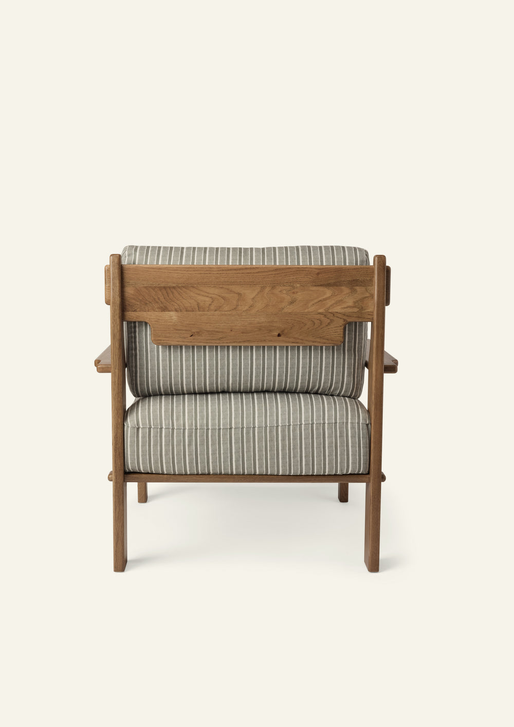 Rear view of the lounge chair showcasing the solid honey oak frame, exposed wood back panel, and green stripe upholstered cushions. Thoughtful craftsmanship highlights the chair from every angle.