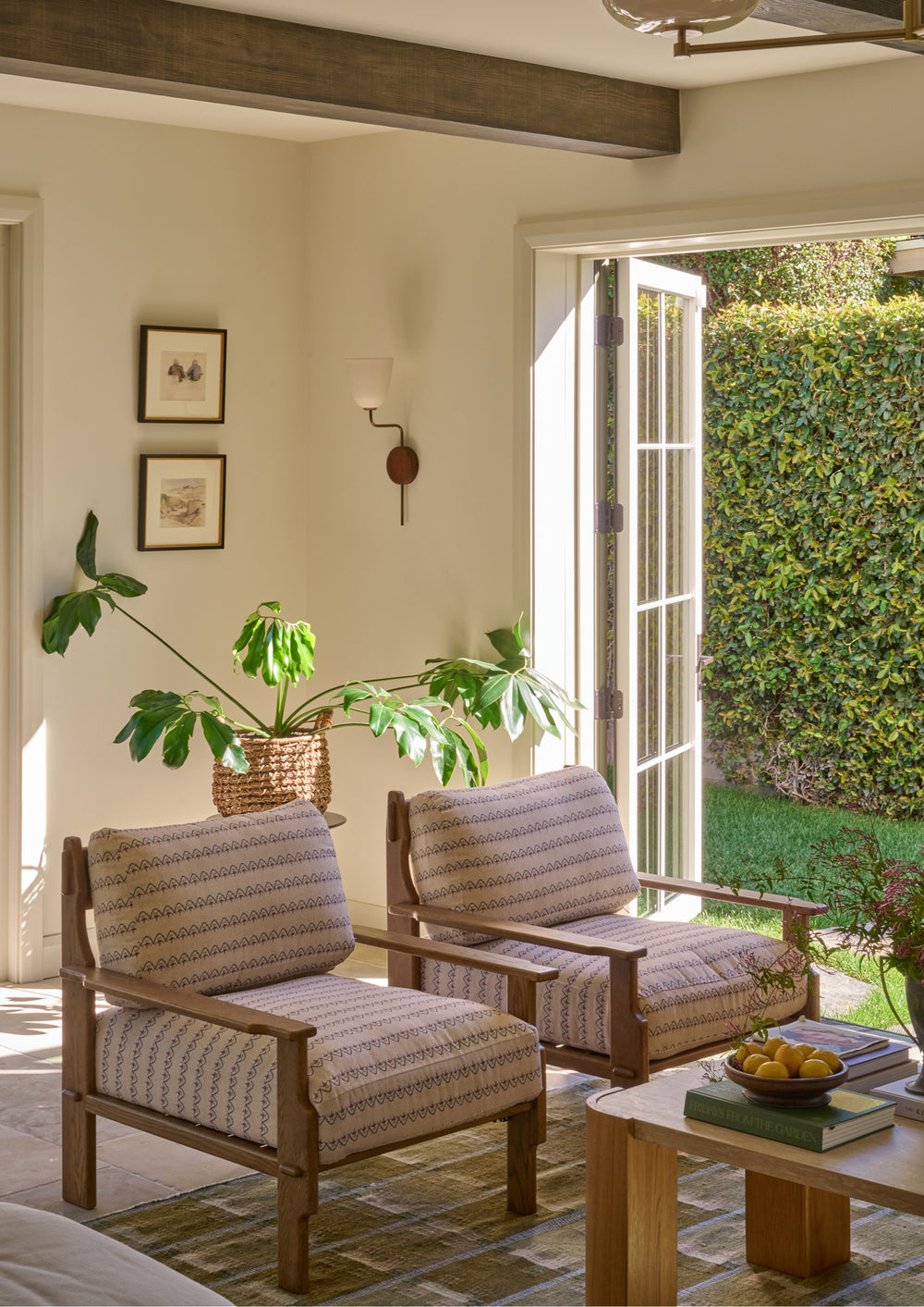 Pair of Neutral Arches lounge chairs styled in a bright living space with open French doors, layered textiles, and natural wood furnishings. The patterned upholstery adds subtle color and texture to the room.