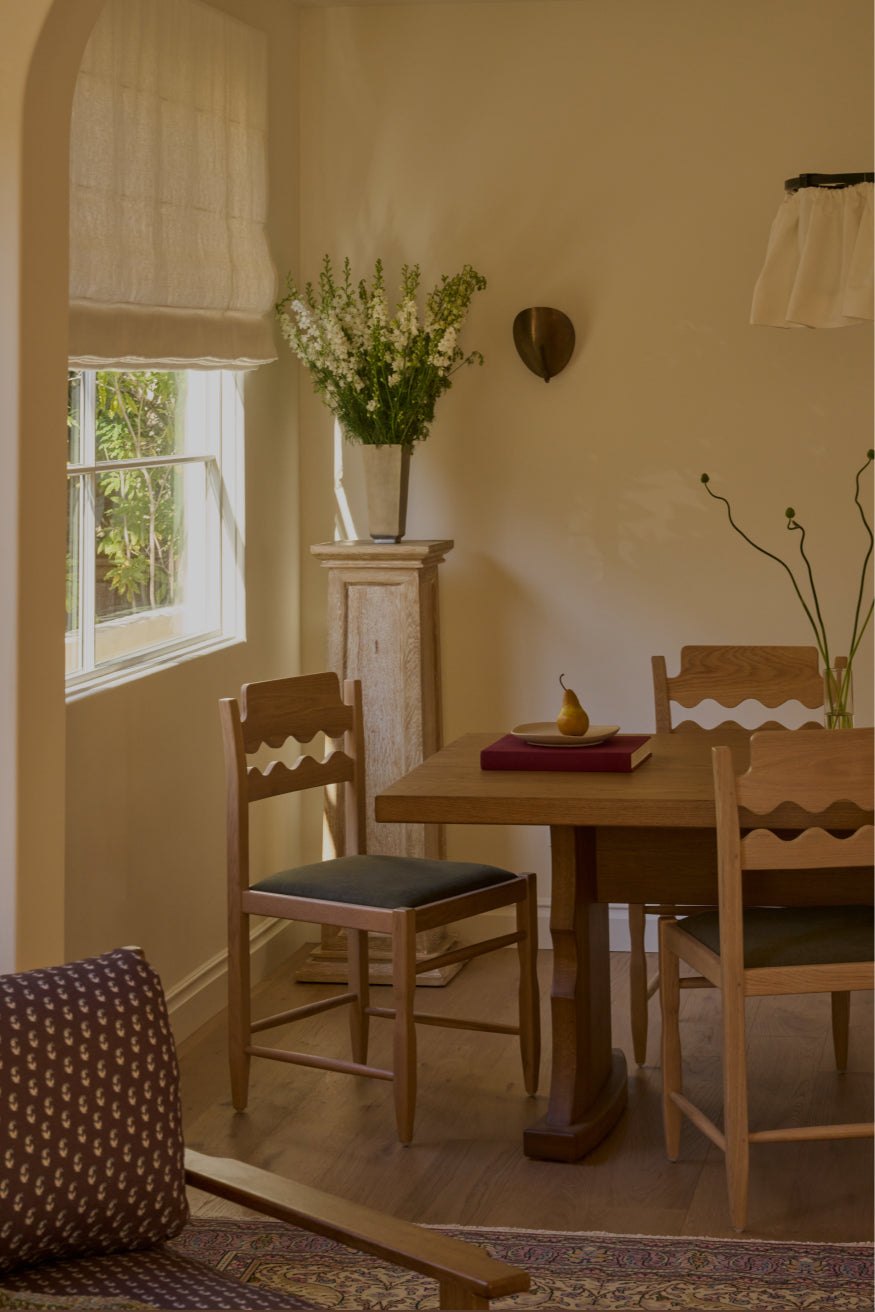 Dining room with Etta honey oak dining table and freda razor dining chairs, window with white curtains, and decorative elements.