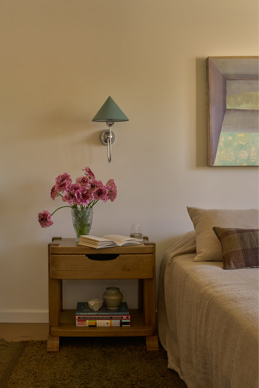 Modern Bedroom with Mina honey oak nightstand, pink flowers, vintage sconce and books.