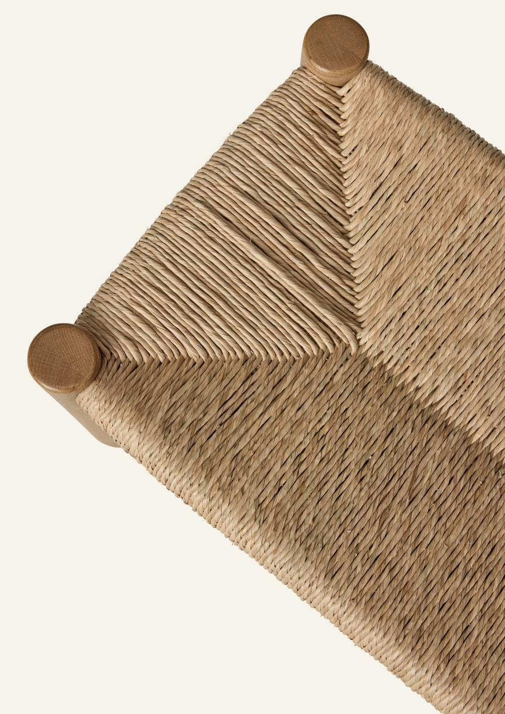 Overhead detail of the bench’s woven natural rush seat, showcasing the intricate handwoven pattern and subtle variations in texture that highlight the craftsmanship of the material.