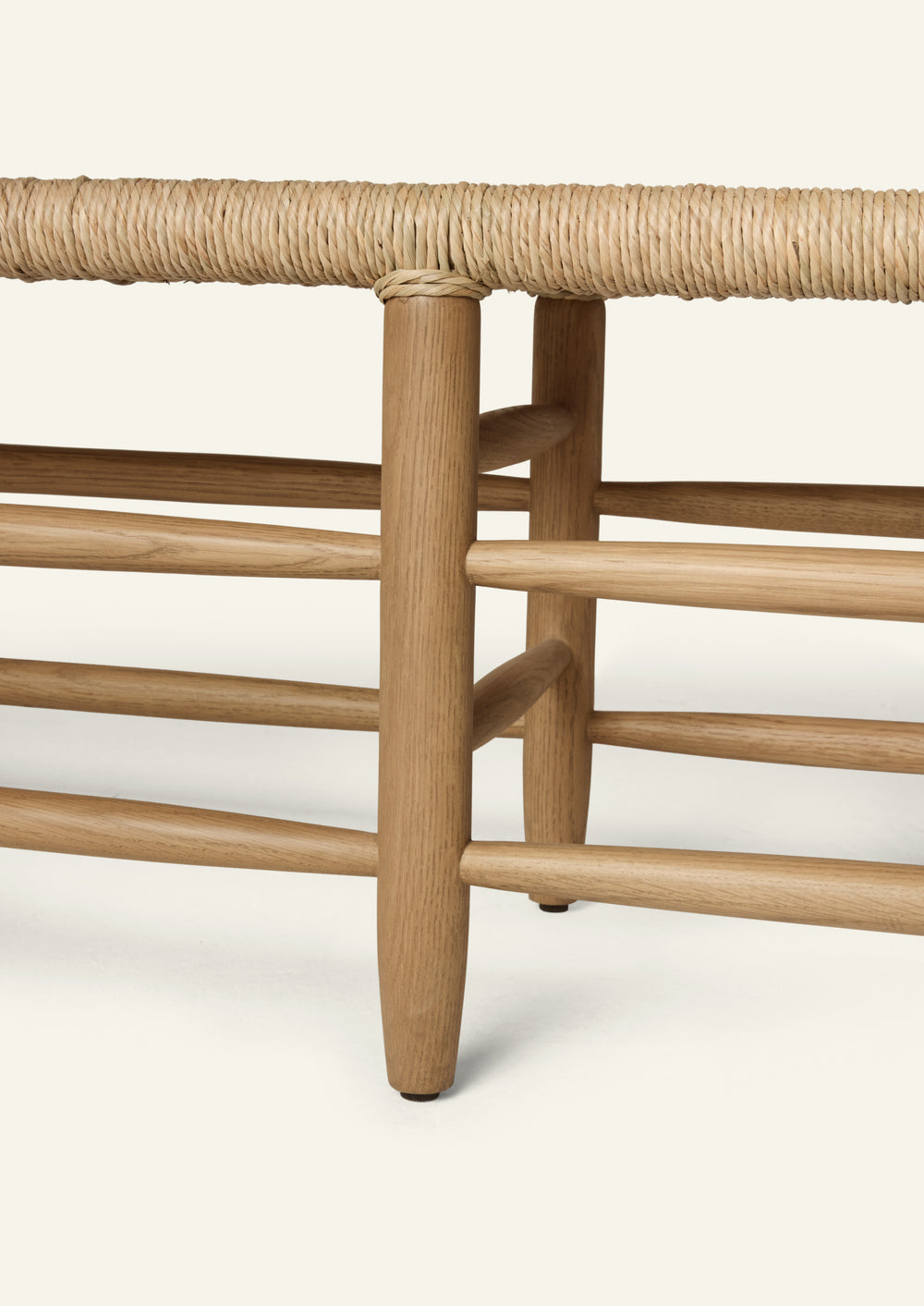 Close-up of the bench’s solid honey oak frame and woven natural rush seat. The image highlights the rounded leg profile, stretcher construction, and handwoven detailing that define the bench’s craftsmanship and character.
