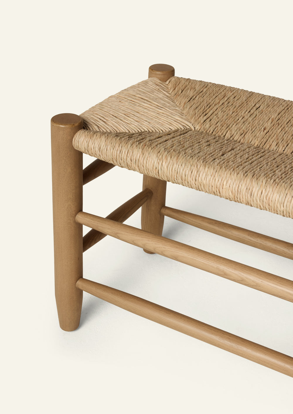 Honey oak bench featuring a handwoven natural rush seat, rounded oak legs, and layered stretcher details. Crafted from solid oak, the bench balances warmth, texture, and timeless simplicity.