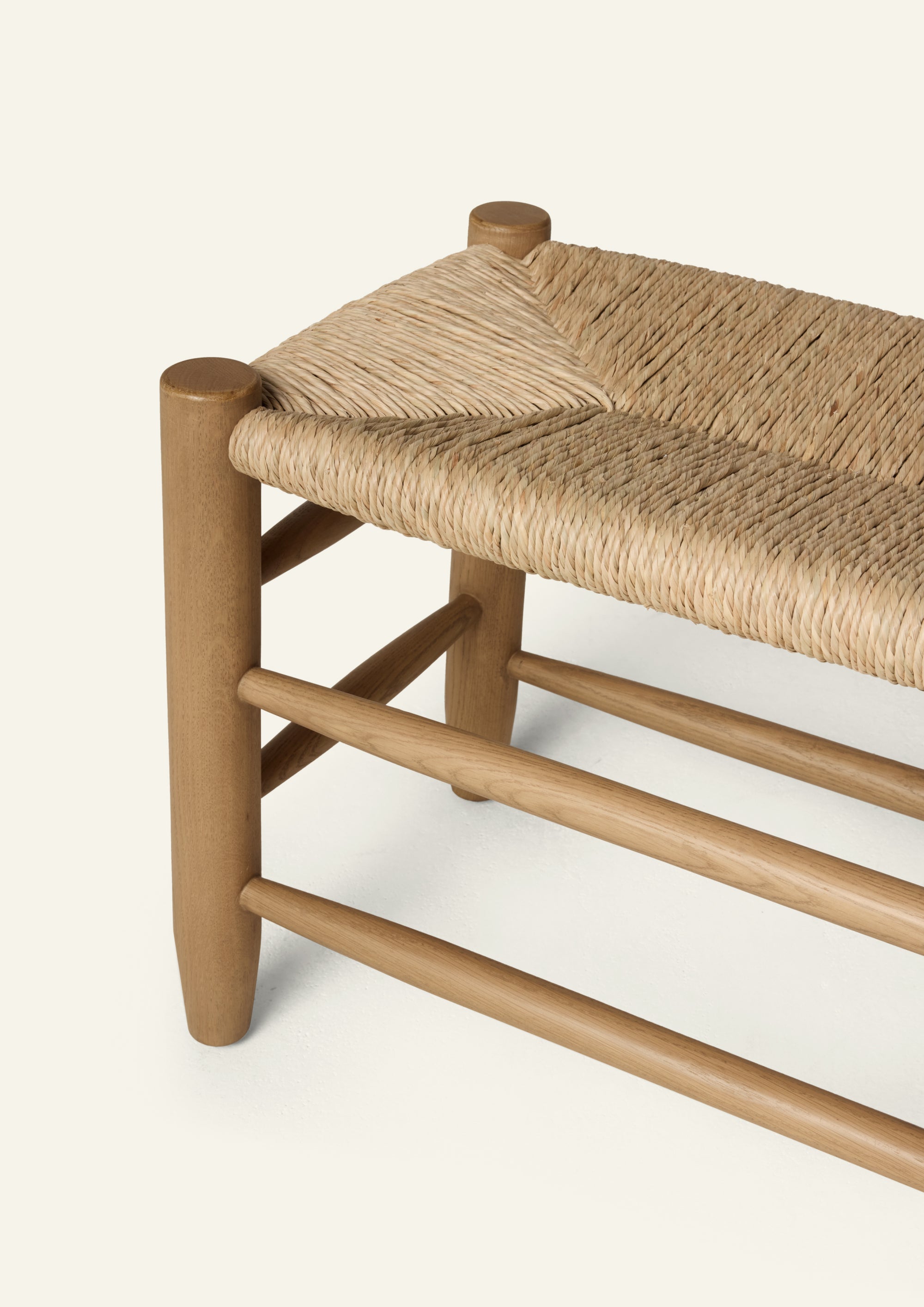 Honey oak bench featuring a handwoven natural rush seat, rounded oak legs, and layered stretcher details. Crafted from solid oak, the bench balances warmth, texture, and timeless simplicity.