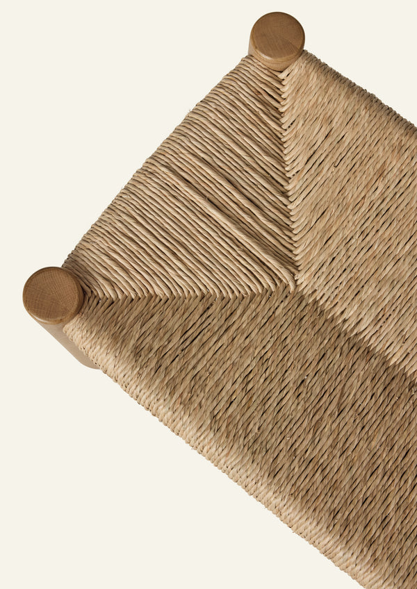Overhead detail of the bench’s woven natural rush seat, showcasing the intricate handwoven pattern and subtle variations in texture that highlight the craftsmanship of the material.