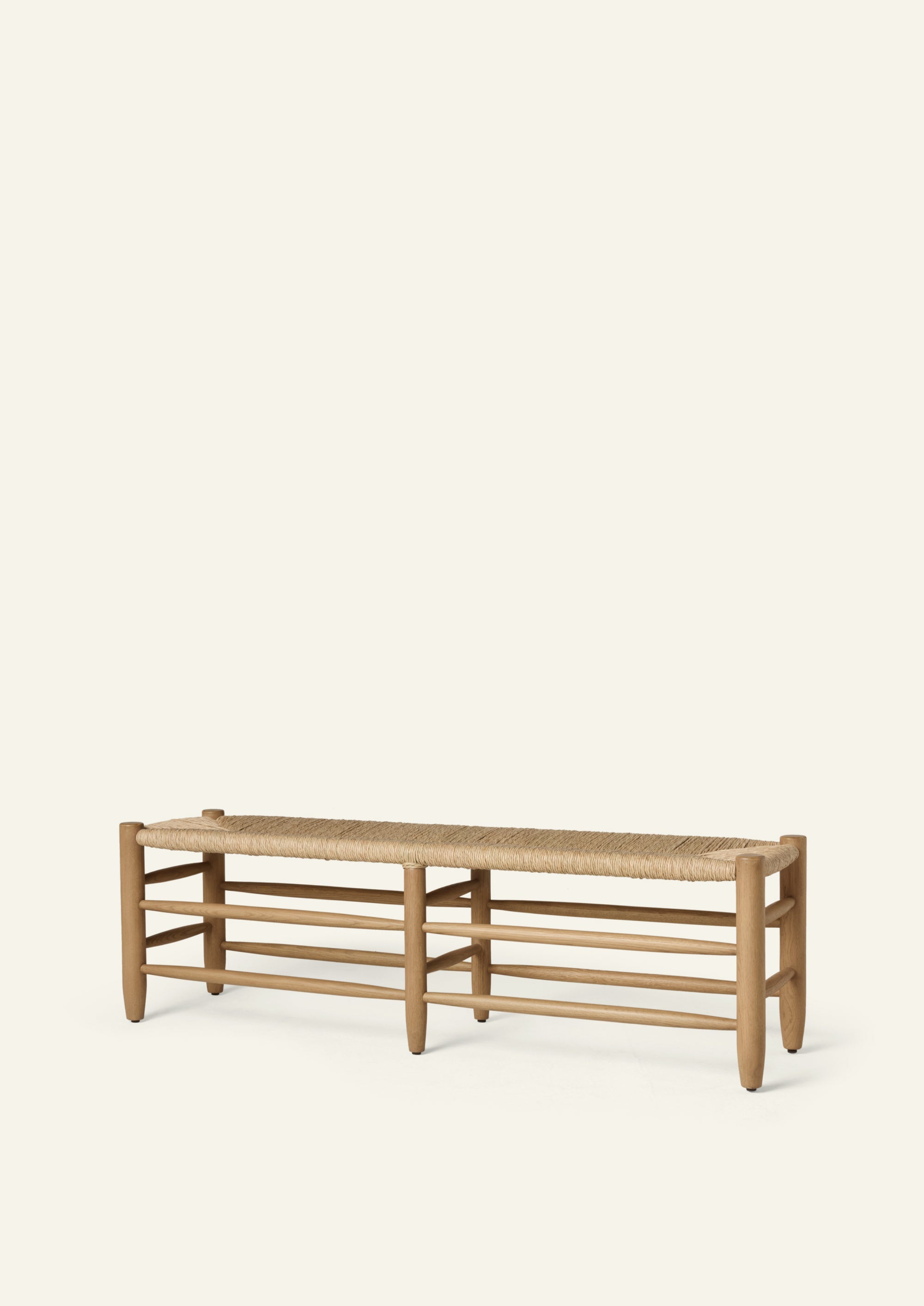 Honey oak bench featuring a handwoven natural rush seat, rounded oak legs, and layered stretcher details. Crafted from solid oak, the bench balances warmth, texture, and timeless simplicity.