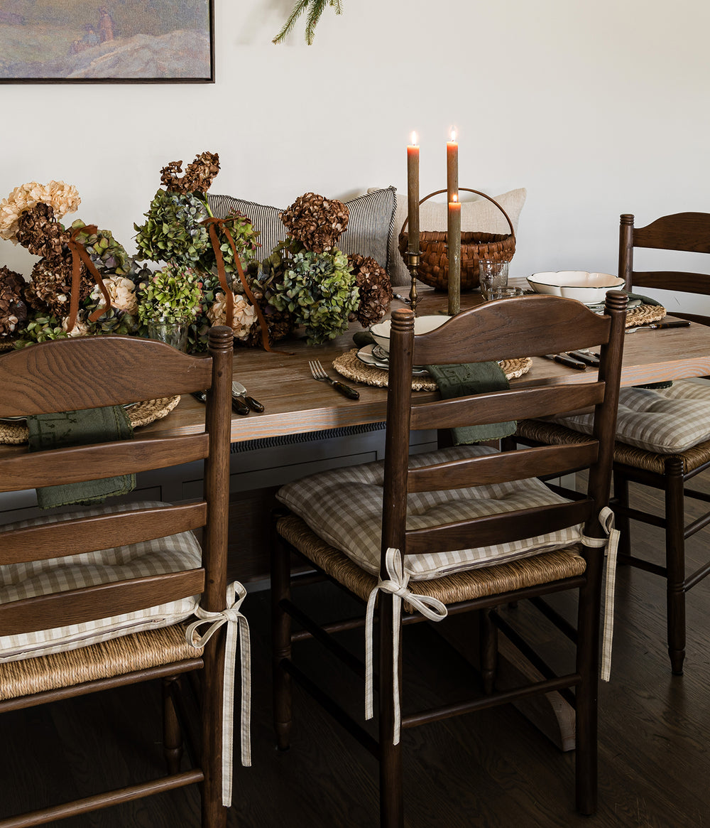Dining room with wooden table and Lea Dining brown oak chairs, decorated with candles and floral arrangements.