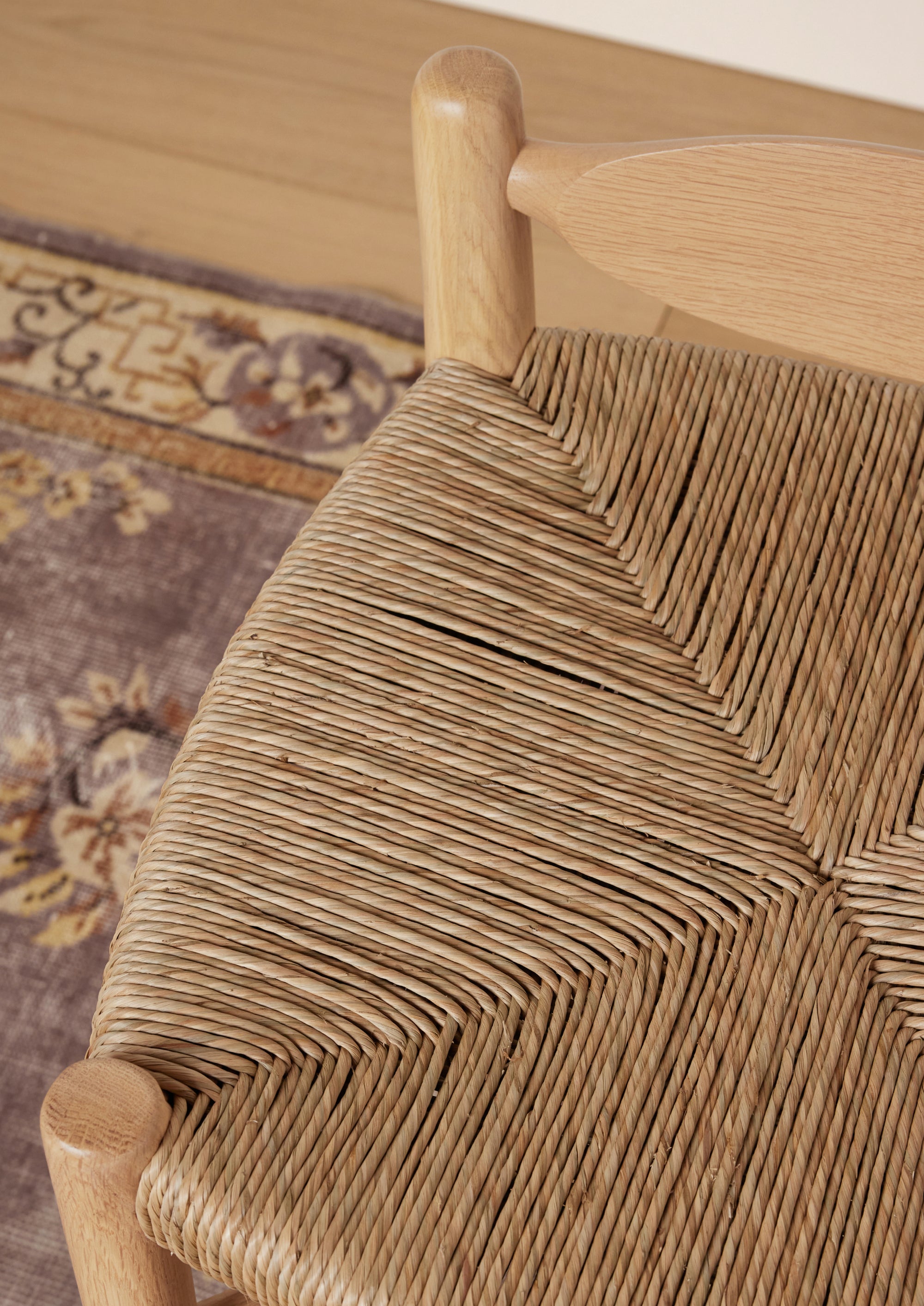 Close-up of the Olma Counter Stool highlighting the handcrafted woven seat, curved backrest, and natural teak grain.
