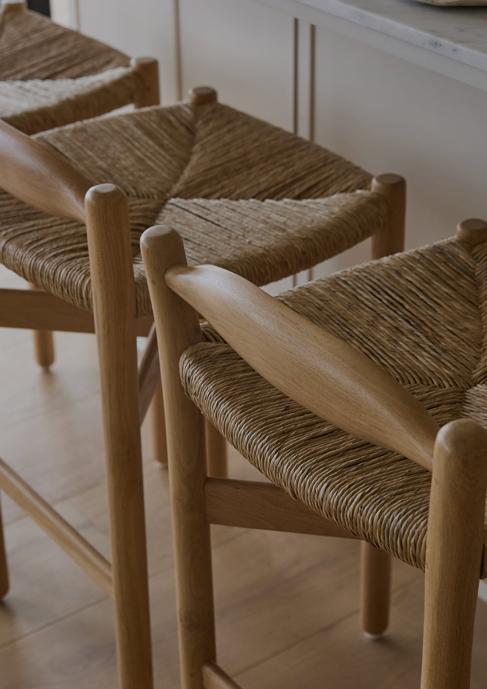 Detail shot of the low profile back of the Olma Counter stool–white oak frame with natural rush seating.
