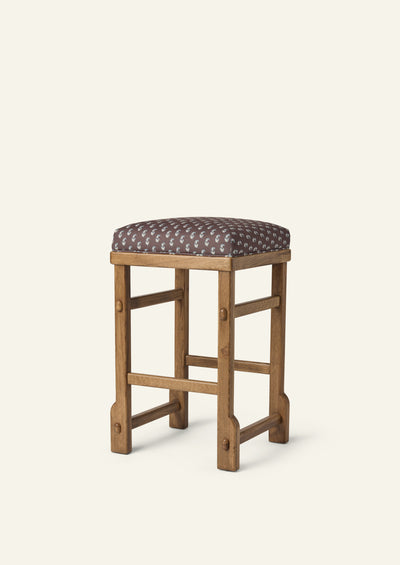 Upholstered counter stool featuring Cocoa Floral fabric atop a solid honey oak frame. The tailored silhouette combines a delicate floral motif with warm wood tones and traditional joinery details.