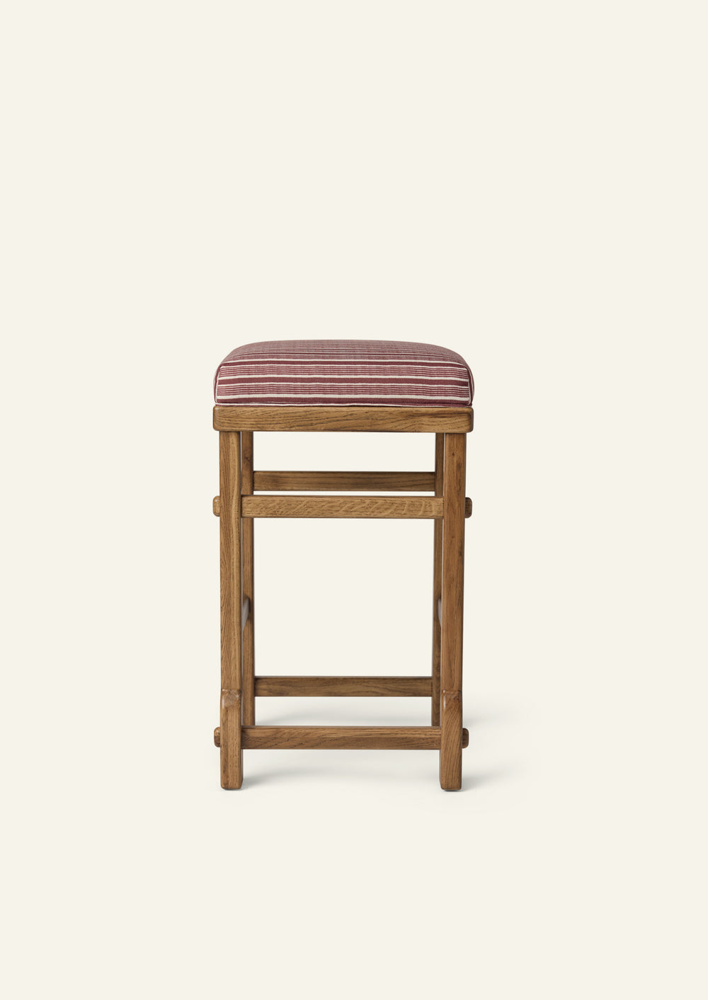 Front view of an upholstered counter stool with a striped cushion and solid honey oak frame. Clean lines, visible joinery, and a classic silhouette make it a versatile addition to kitchens and dining spaces.