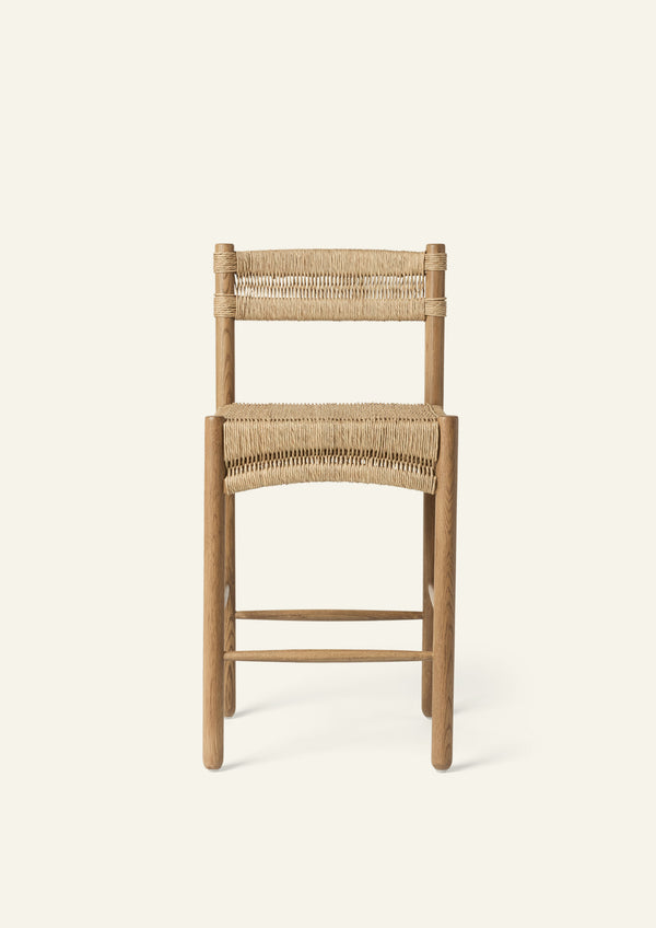 Front view of the counter stool featuring a woven rush seat and backrest supported by a solid honey oak frame. The gently curved seat detail provides visual softness and everyday comfort.