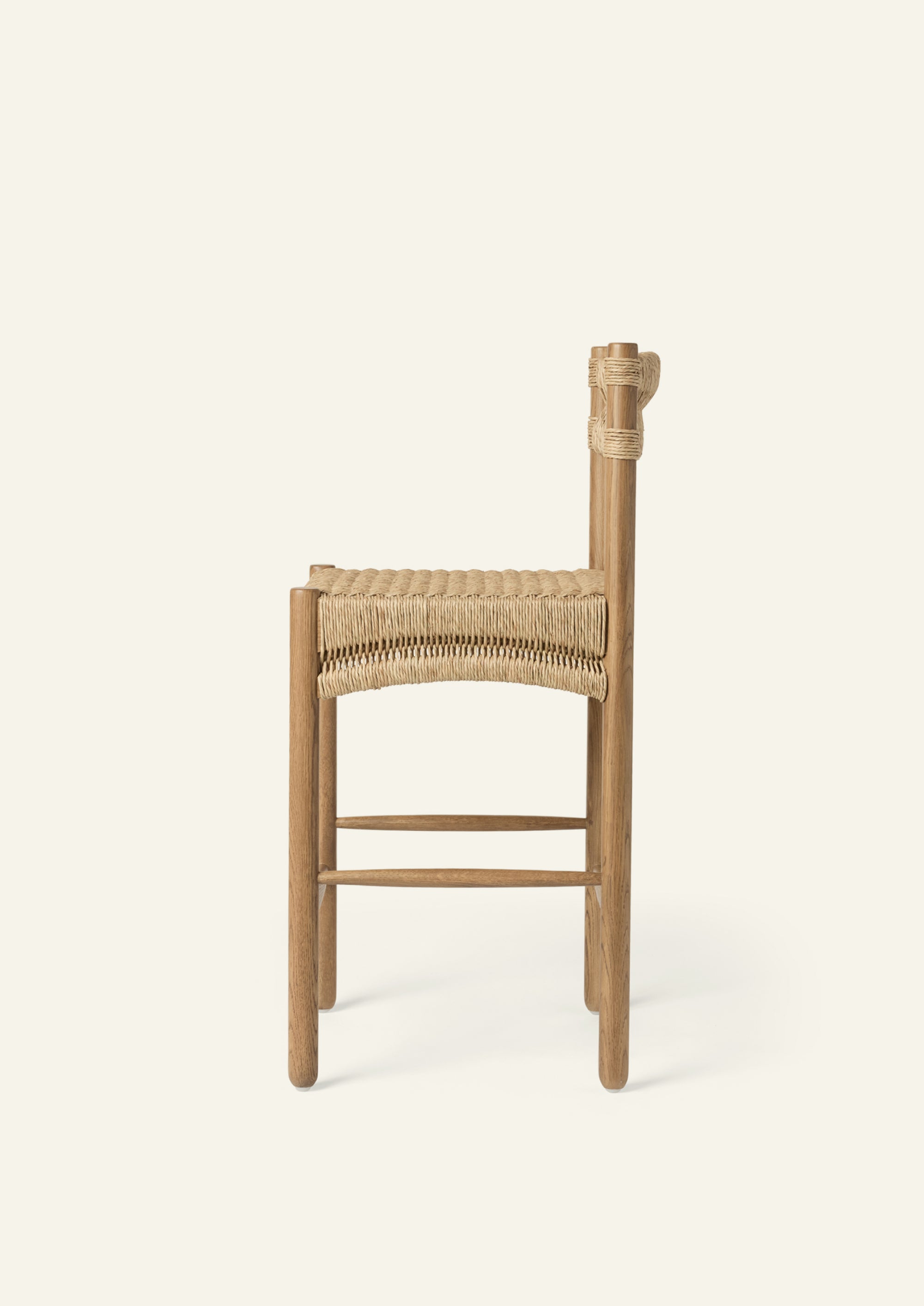 Side profile of the counter stool highlighting its woven seat, supportive backrest, and solid oak frame. The streamlined silhouette balances durability, comfort, and understated style.
