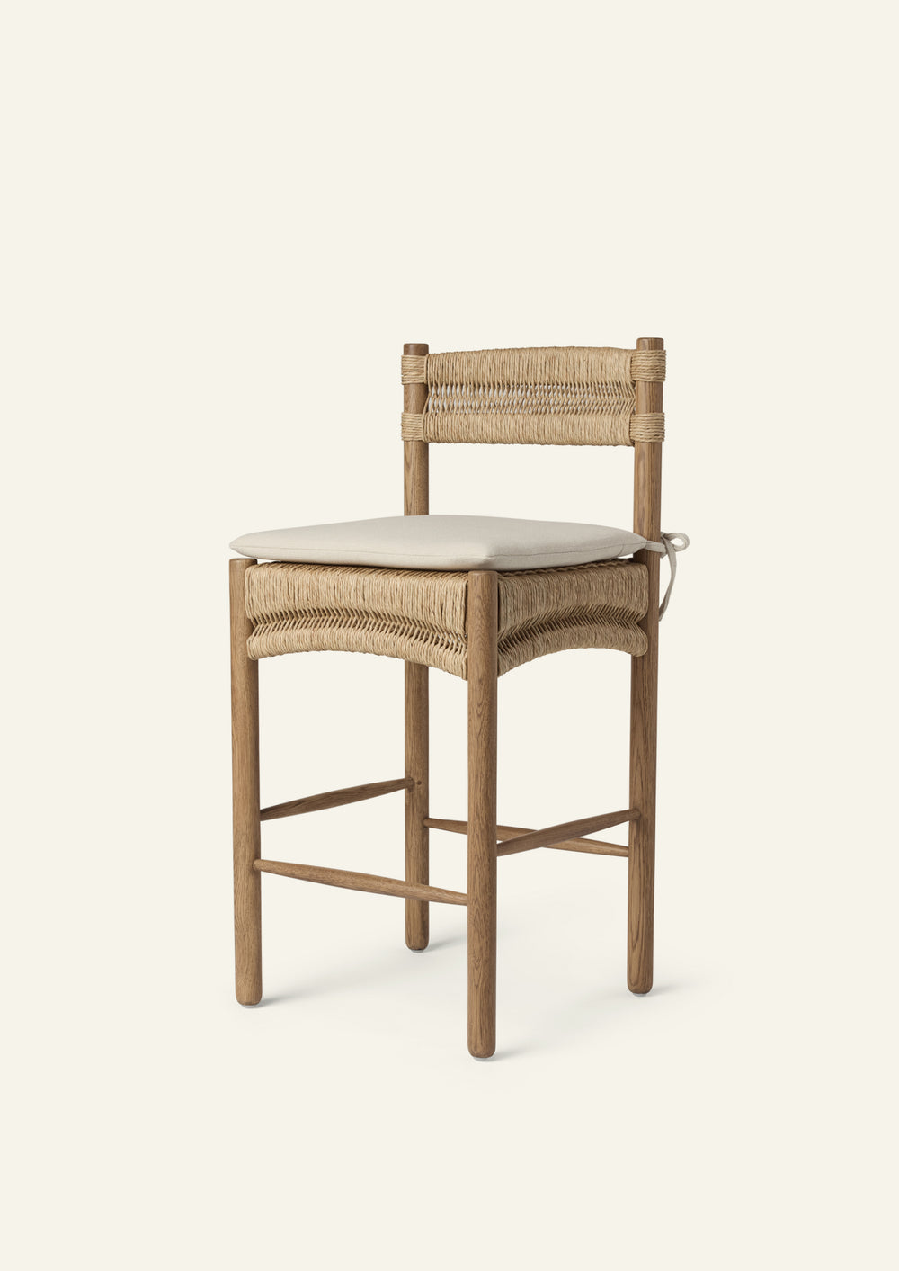 Three-quarter view of a counter stool crafted from solid honey oak and handwoven natural rush with a custom made seat cushion in an ivory performance tweed fabric. 