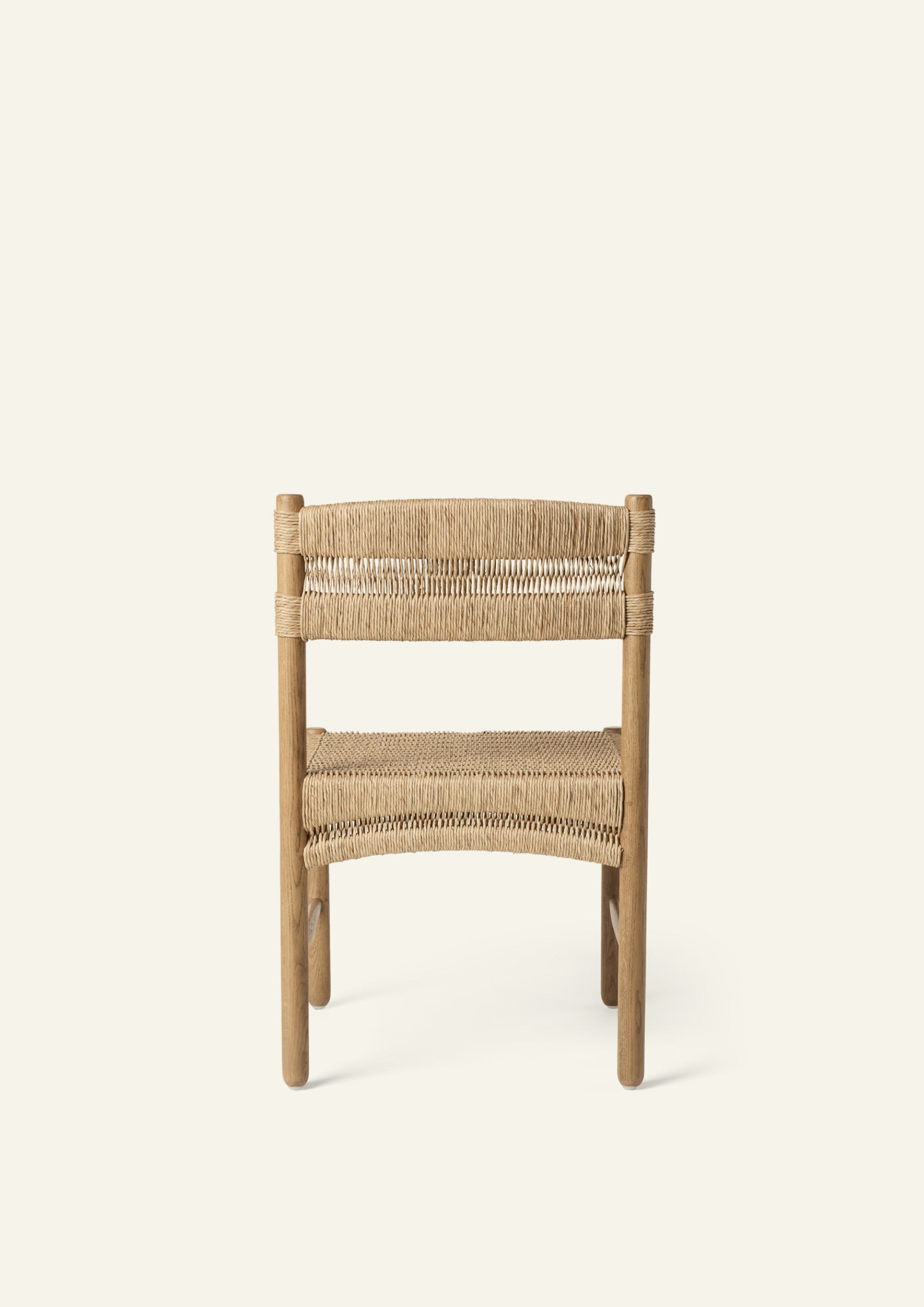 Rear view of the dining chair showcasing a woven rush backrest secured around solid oak posts. The exposed natural materials and clean lines highlight the chair’s handcrafted character.