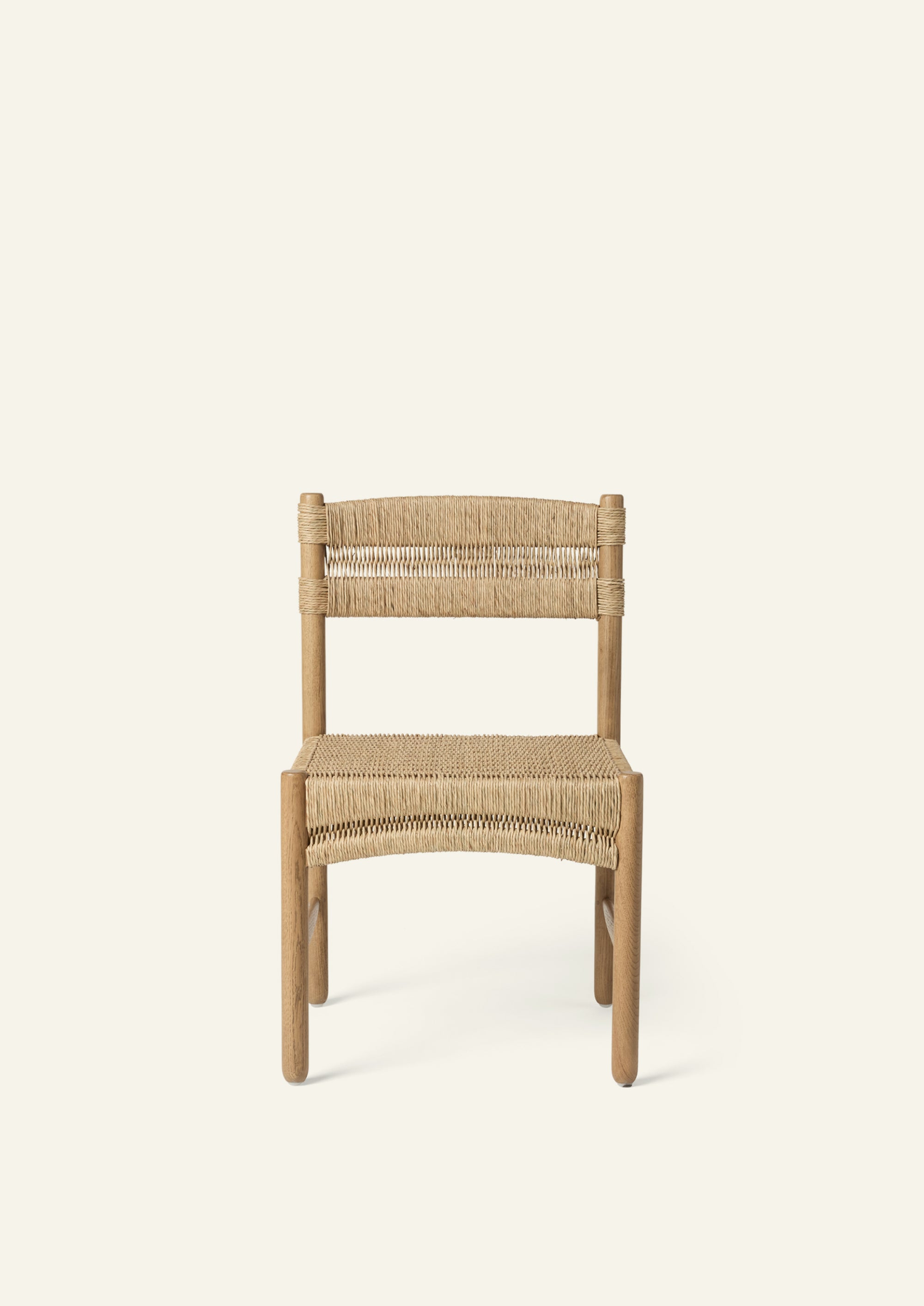 Front view of the dining chair featuring a woven rush seat and backrest supported by a solid honey oak frame. The gently curved seat profile adds visual softness and comfort.