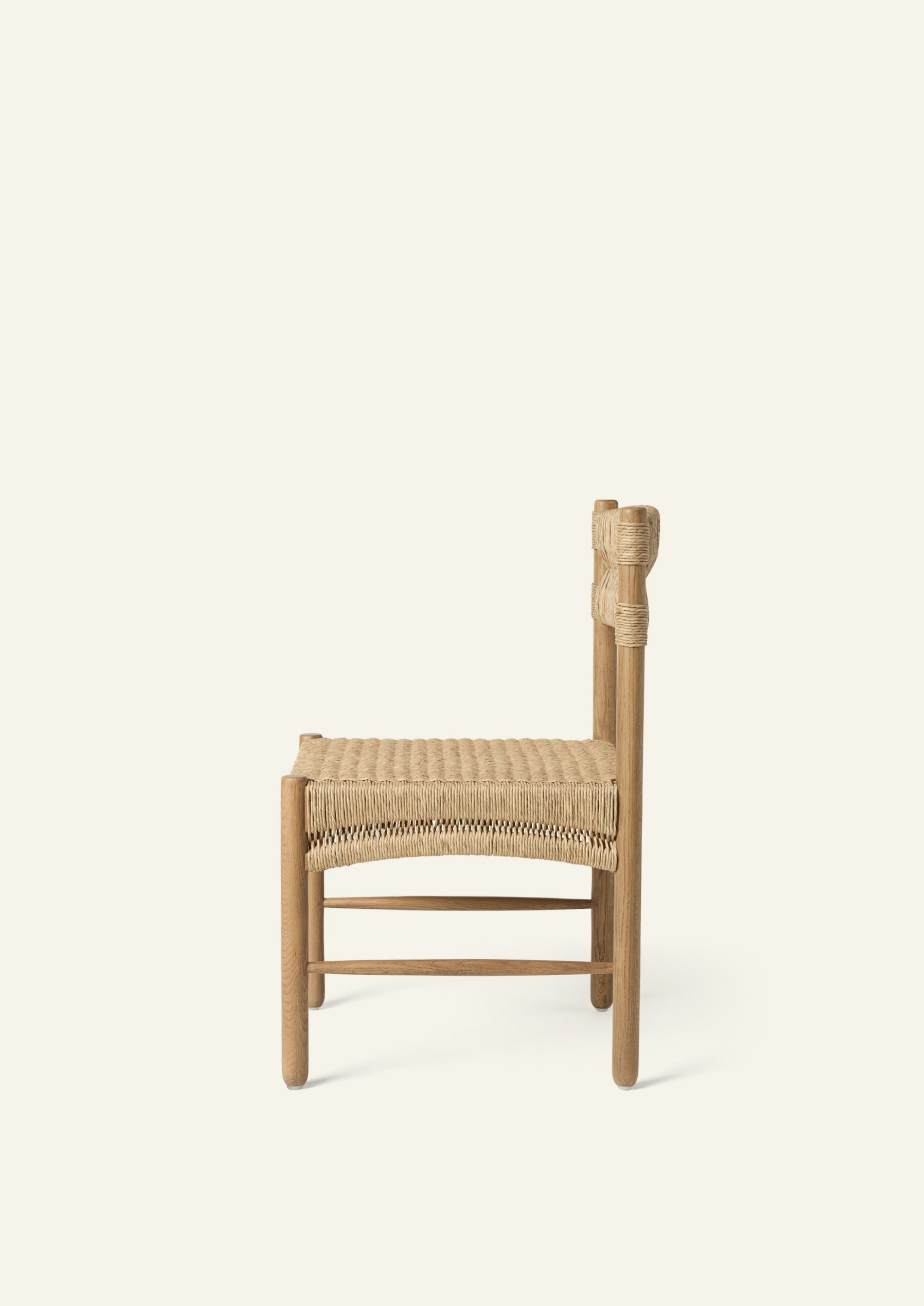 Side profile of the dining chair highlighting its woven rush seat, supportive backrest, and solid oak frame. The streamlined design balances durability, comfort, and relaxed elegance.
