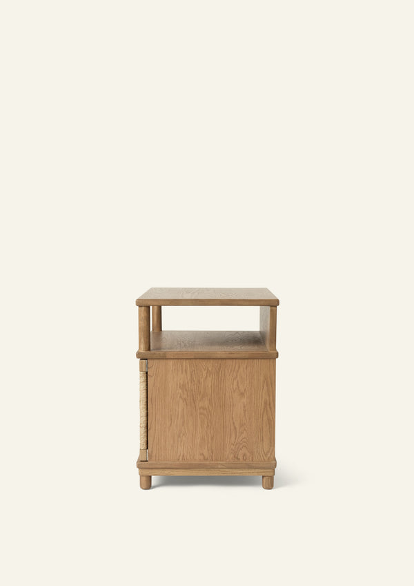 Side profile of the honey oak nightstand showing the open upper shelf, enclosed cabinet storage, and compact footprint. The design offers versatile storage while maintaining a clean, streamlined silhouette.