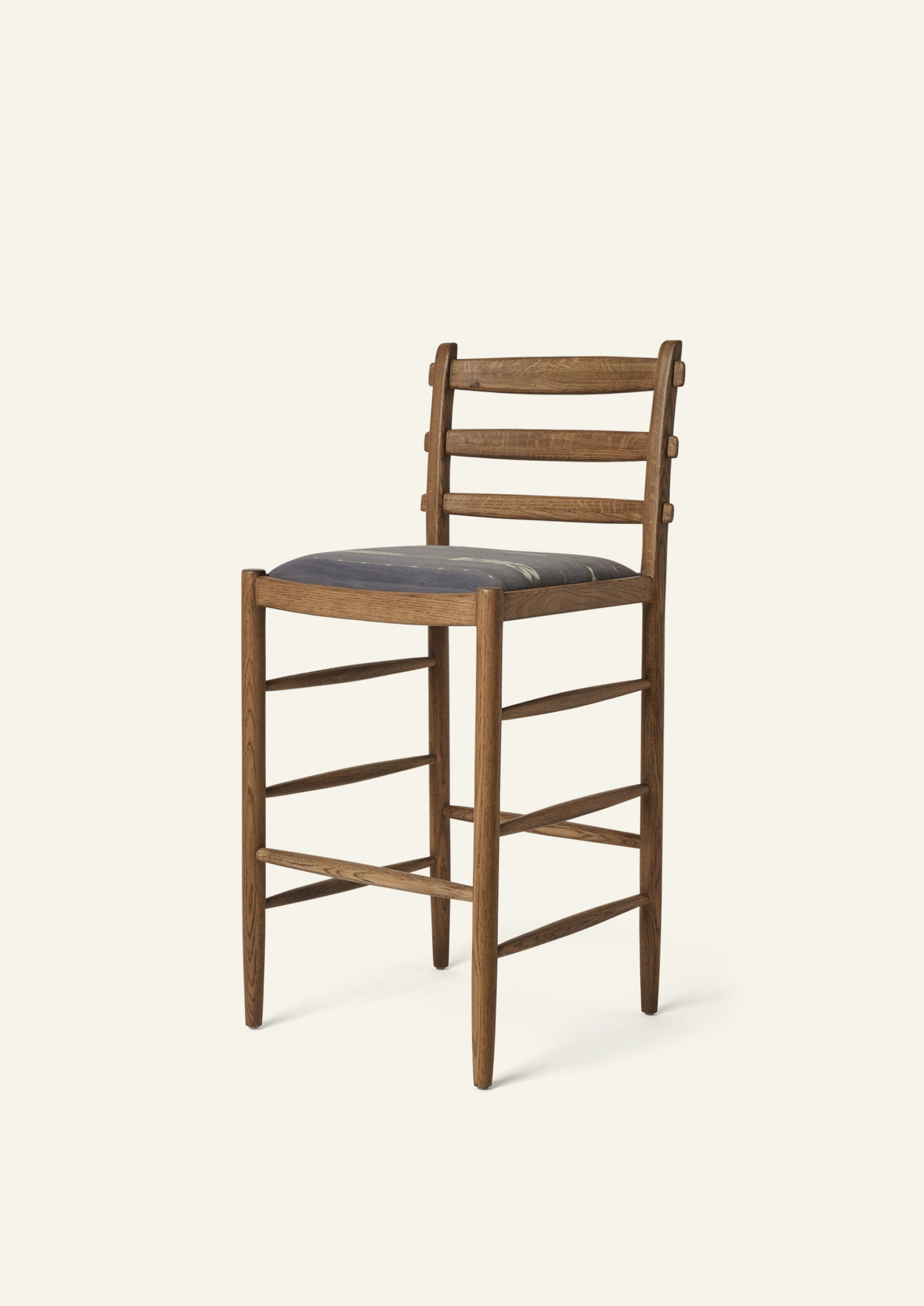 Tiga Counter Stool with a solid honey oak frame and a custom upholstered seat, shown from an angled front view on a neutral background.