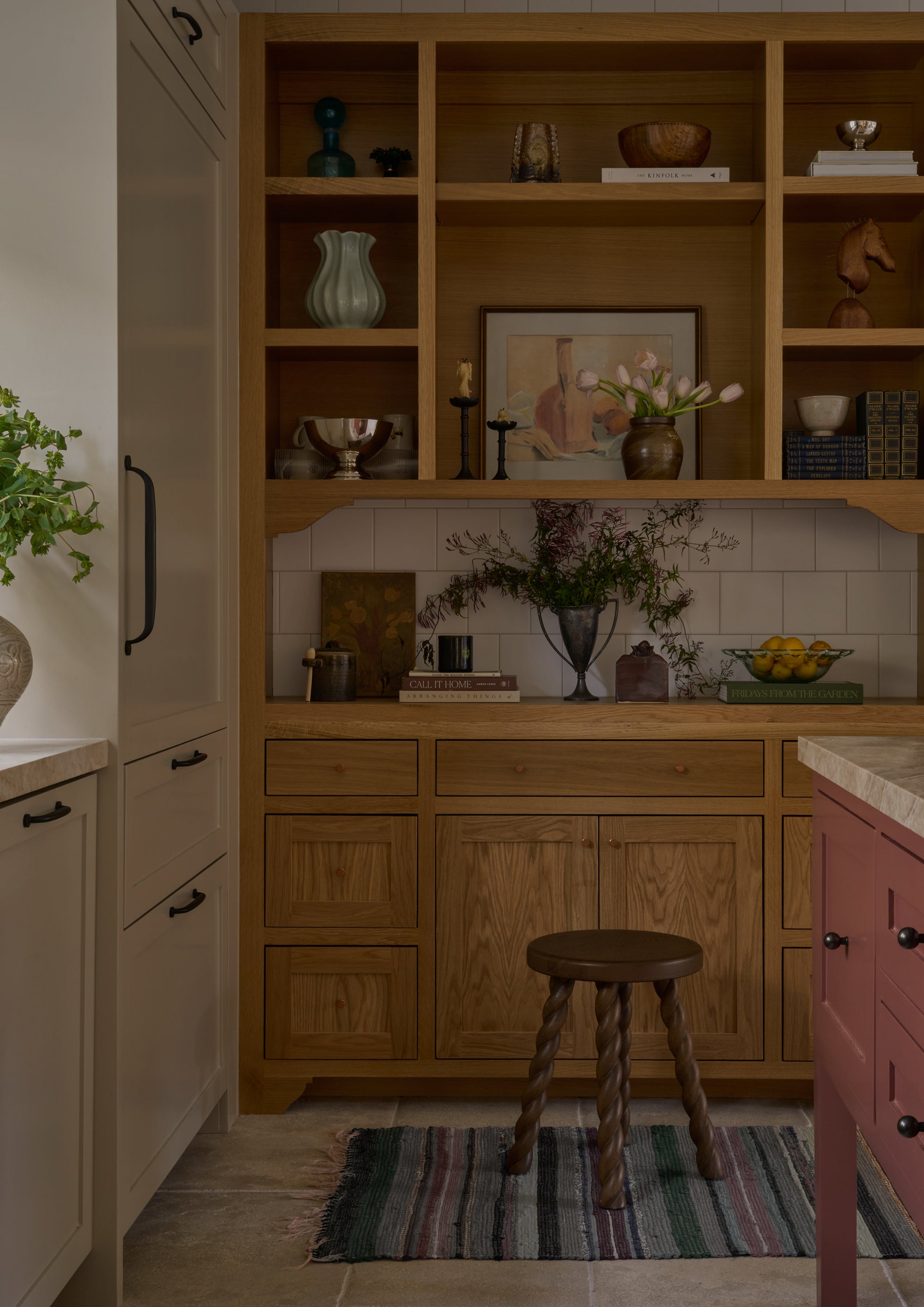 Brown oak accent stool styled in a kitchen with warm wood cabinetry and open shelving. The sculptural spiral legs add a whimsical, collected feel while complementing the natural materials throughout the space.