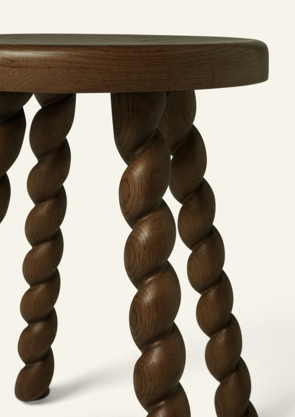 Close-up of the stool’s hand-finished spiral-turned oak legs, highlighting the sculptural detailing, rich brown tone, and visible wood grain.