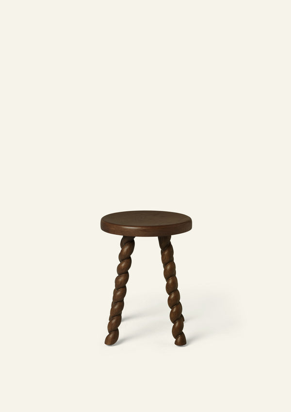 Front-facing view of a round brown oak accent stool with four spiral-turned legs and a warm brown finish. The simple form and sculptural detailing create a timeless accent piece.