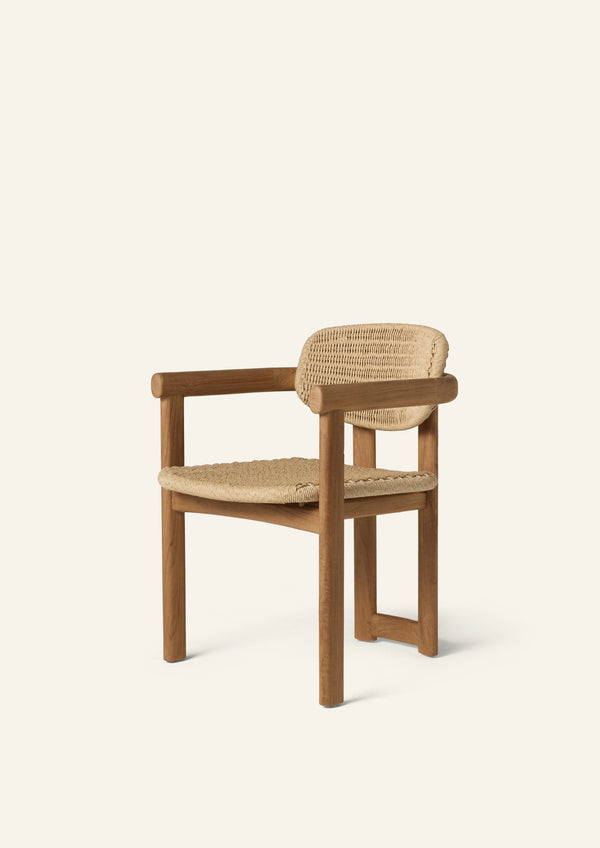 Three-quarter view of an outdoor dining armchair crafted from solid teak and woven synthetic paper cord. Rounded arms, a woven seat, and a curved woven backrest create a comfortable silhouette designed for both indoor and outdoor living.