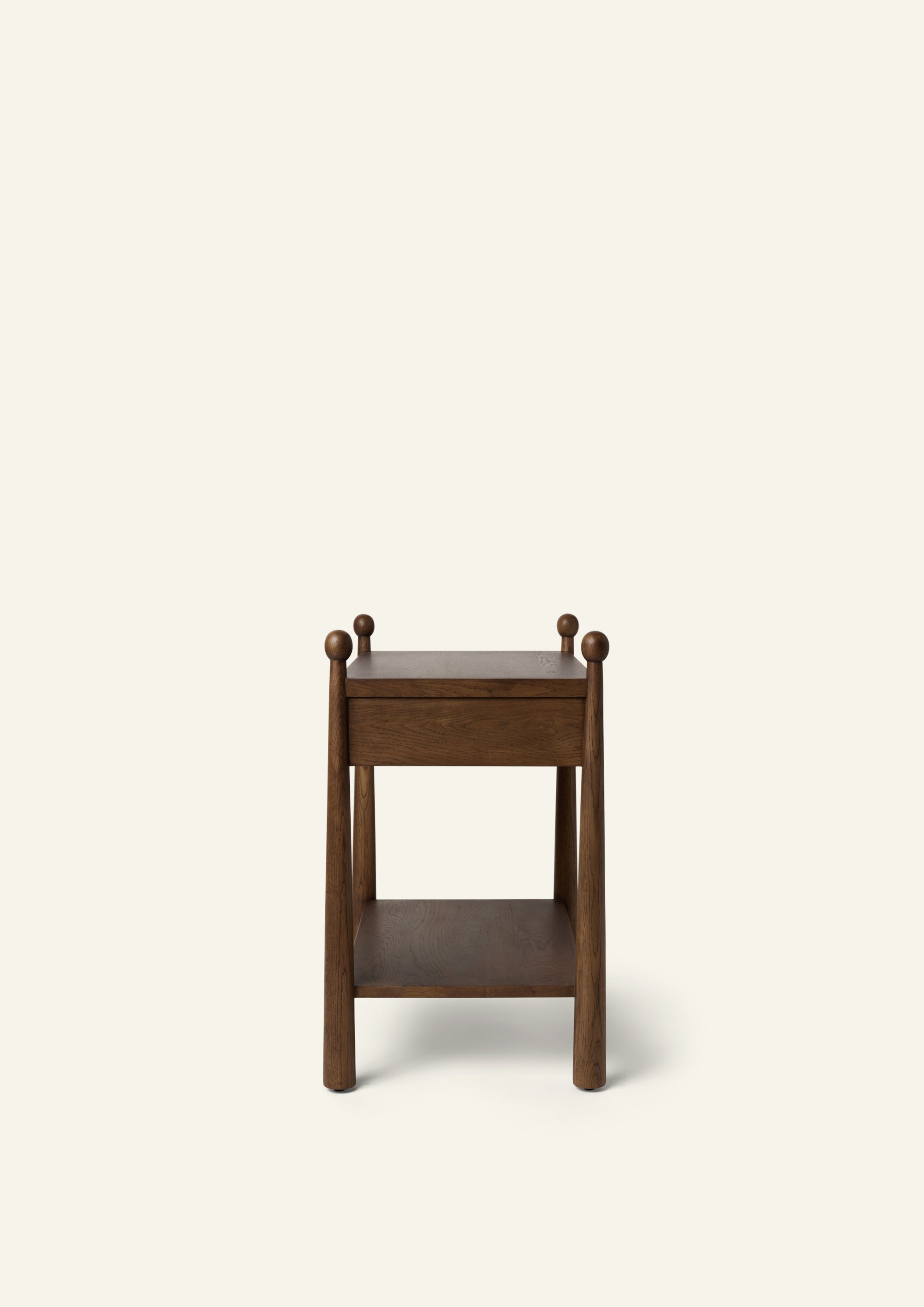 Side profile of a dark oak nightstand featuring a single drawer, open lower shelf, tapered cylindrical legs, and rounded finials. The clean silhouette highlights the balance between traditional detailing and functional storage.