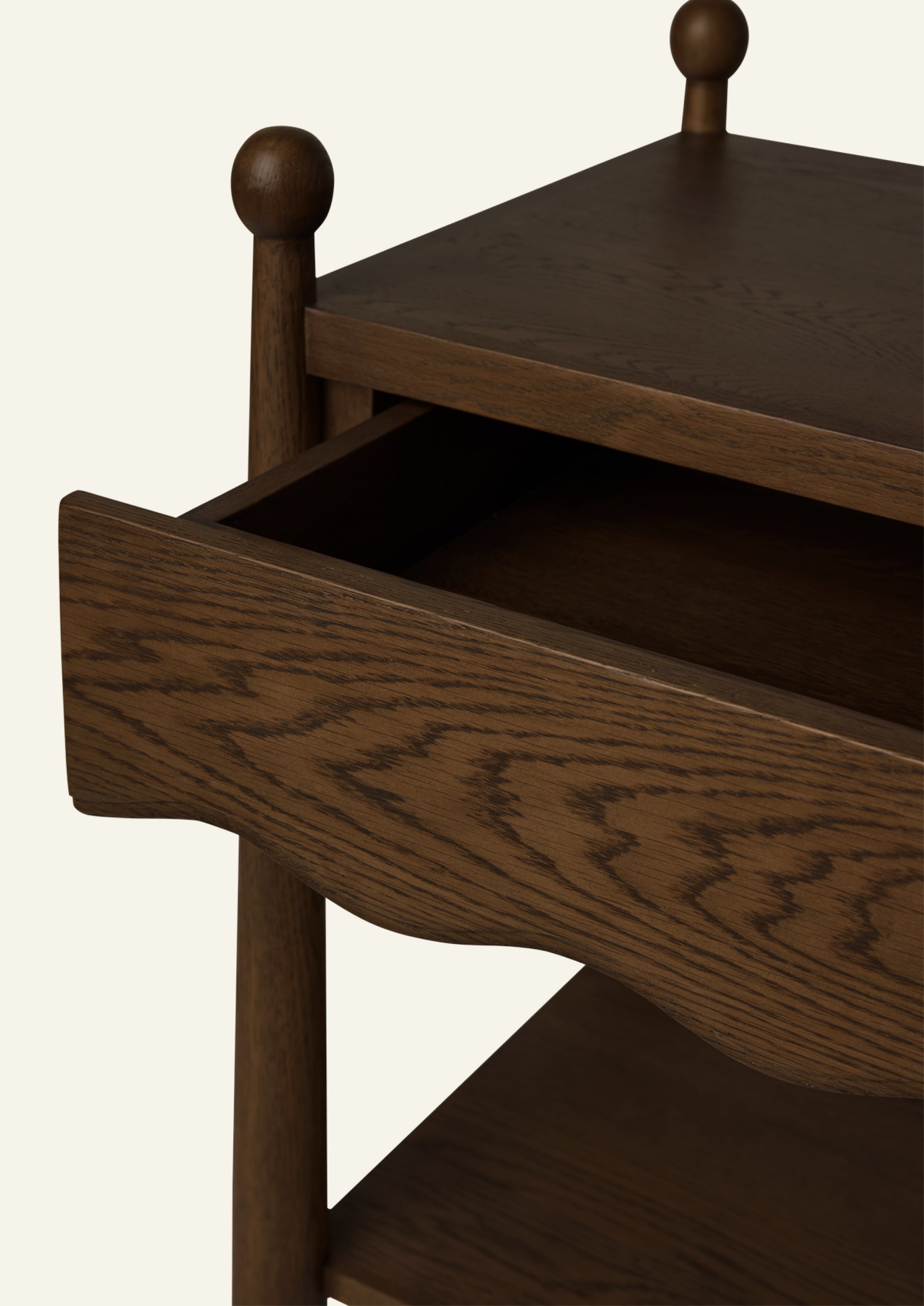 Close-up of a partially opened drawer on a brown oak nightstand, showcasing the pronounced oak grain, spacious interior storage, and signature scalloped drawer front.