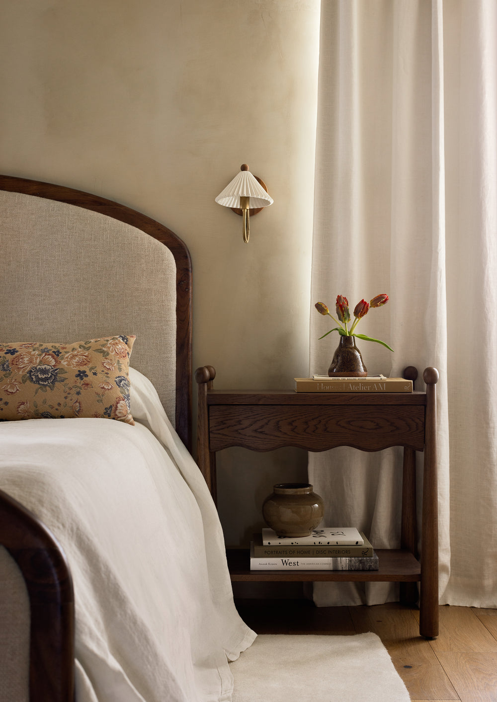 A modern traditional bedroom with the Wave brown oak nightstand, wood paneled bed and floral pillow accent in a neutral space. 
