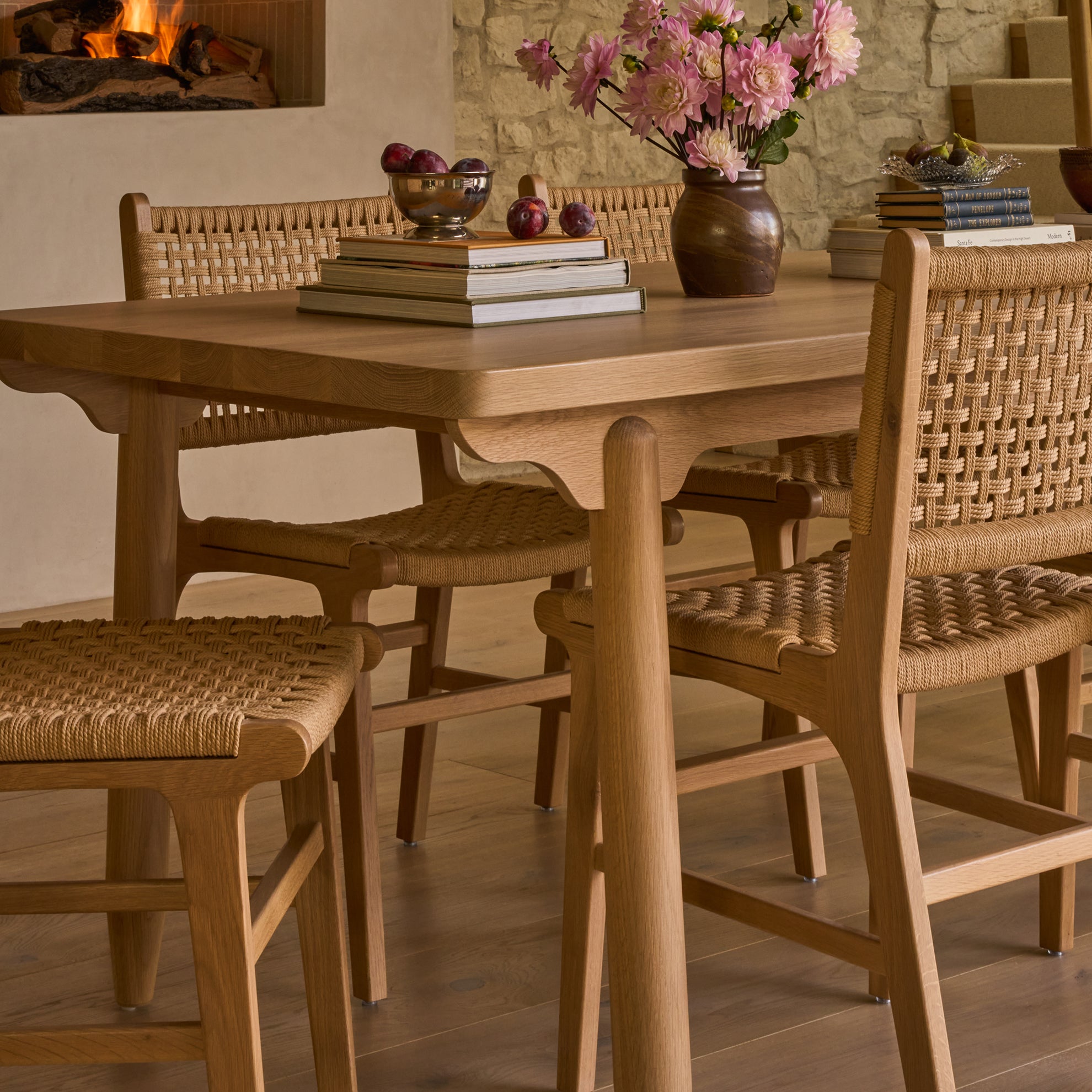 Wooden dining table with chairs in a warm-toned room.