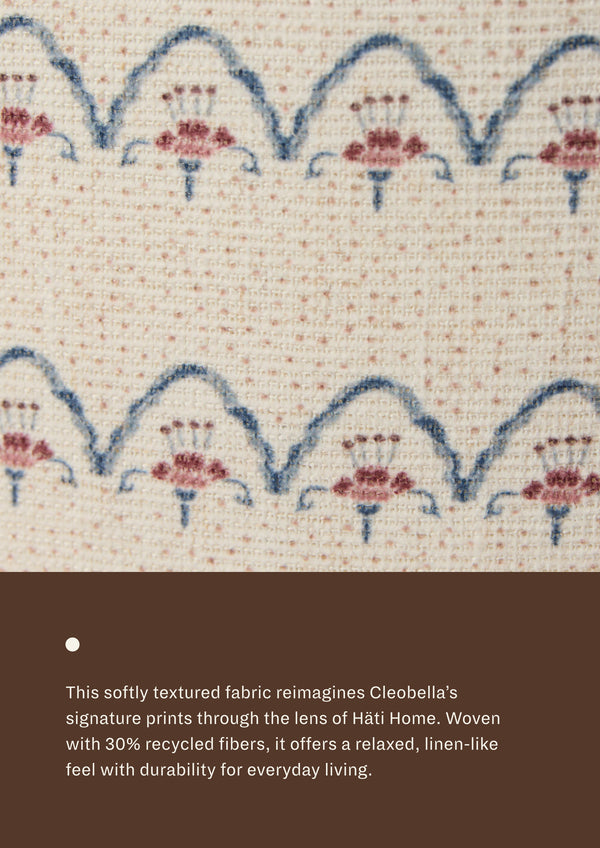Close-up of the Neutral Arches fabric, featuring repeating blue scalloped lines and dusty rose floral-inspired motifs on a soft cream woven ground. The textured textile offers a relaxed, linen-like appearance with subtle dimension.