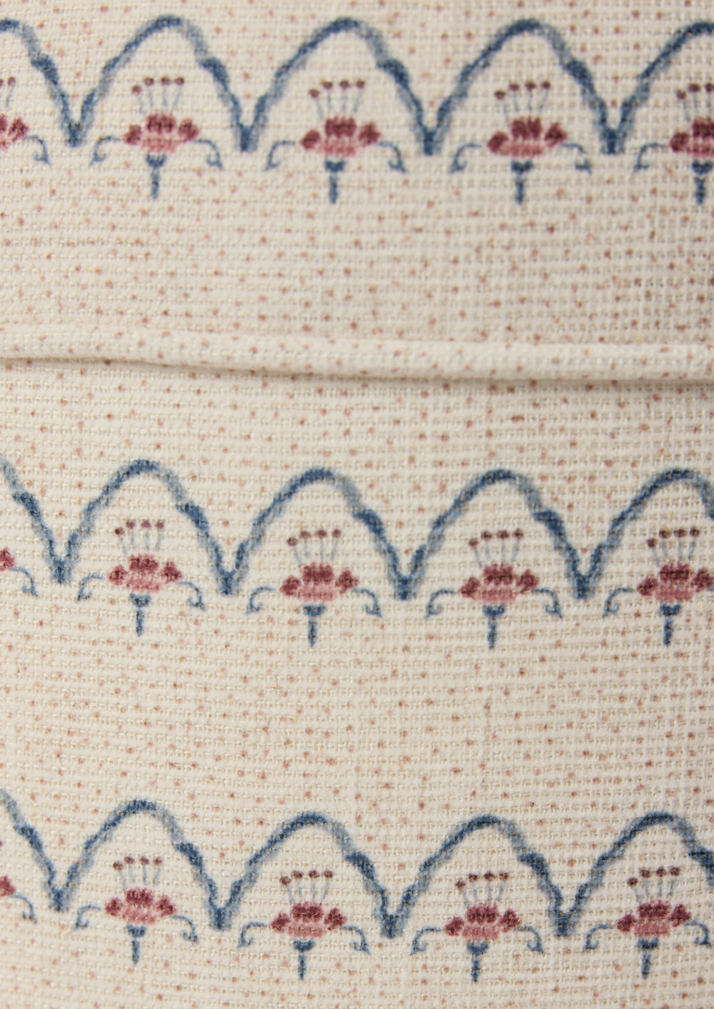 Close-up shot of the Cleobella Neutral arches fabric. Small dots around a floral arch pattern on an ivory base.