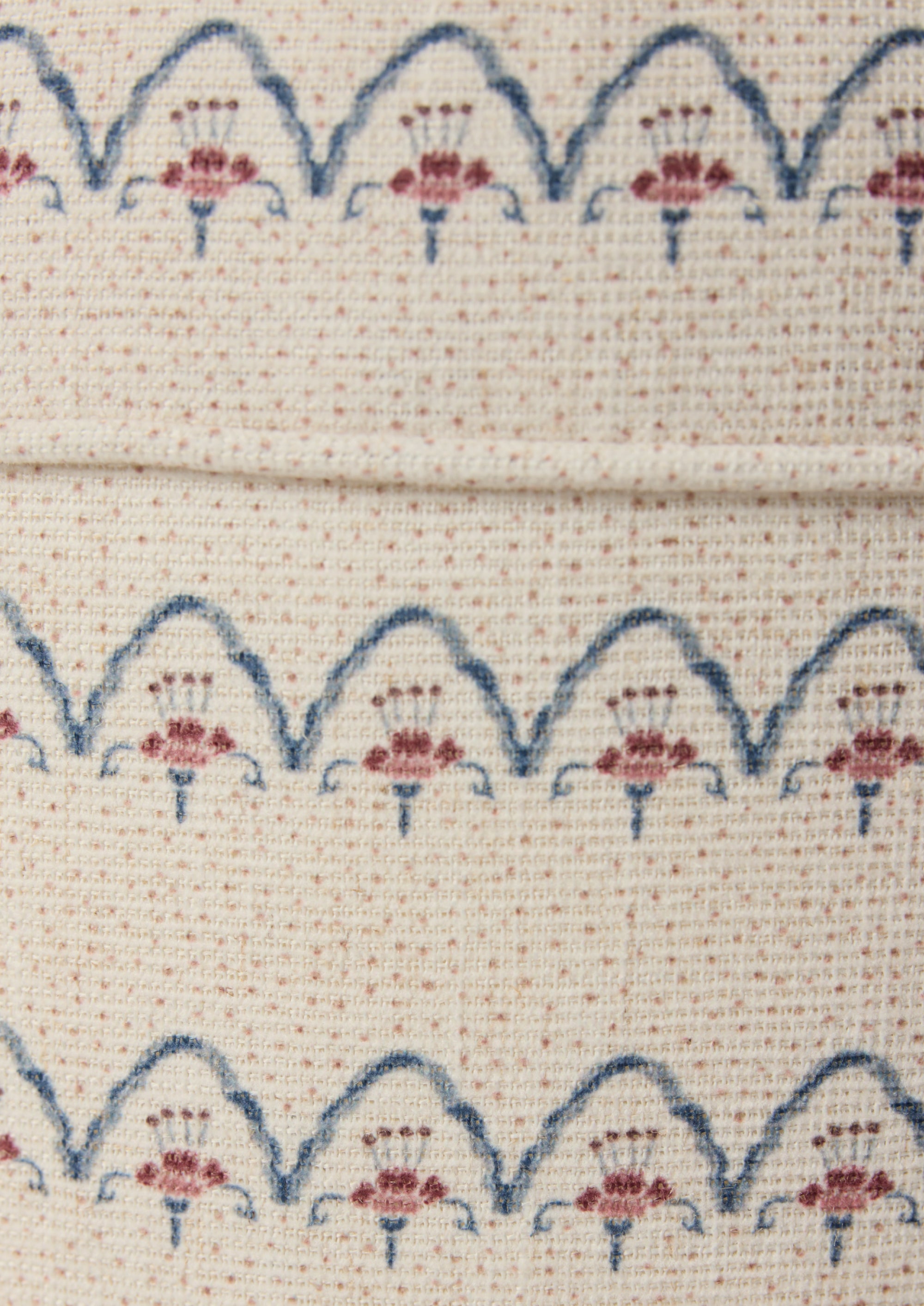 Close-up shot of the Cleobella Neutral arches fabric. Small dots around a floral arch pattern on an ivory base.