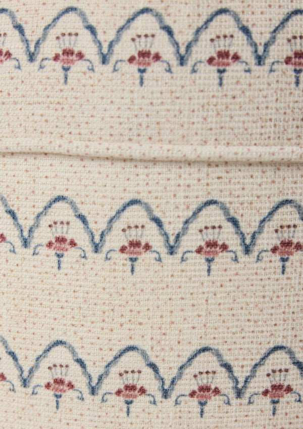 Close-up shot of the Cleobella Neutral arches fabric. Small dots around a floral arch pattern on an ivory base.