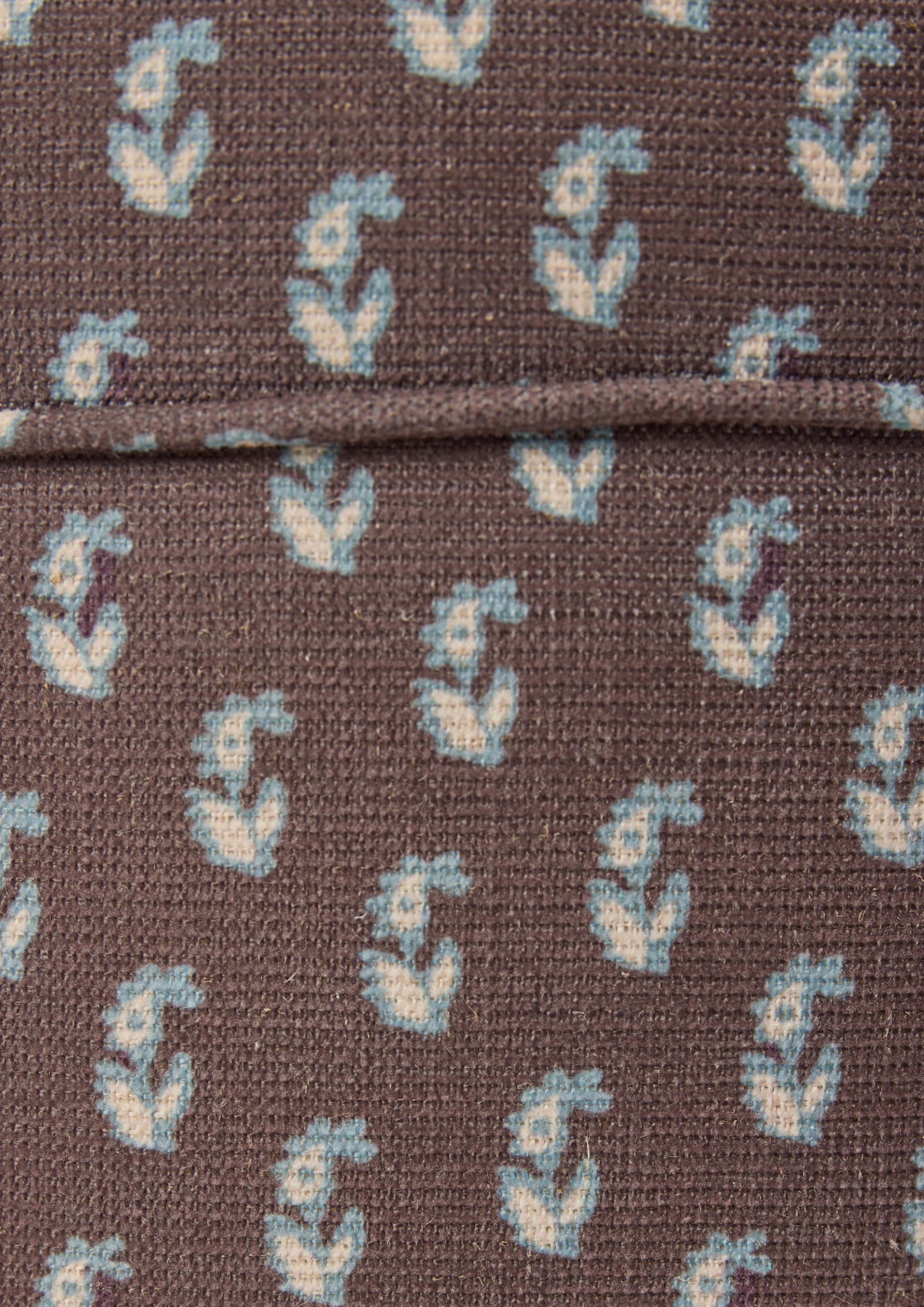 Close-up of the Cocoa Floral fabric by Cleobella. A cool brown base with individual paisleys in ivory with a blue outline.