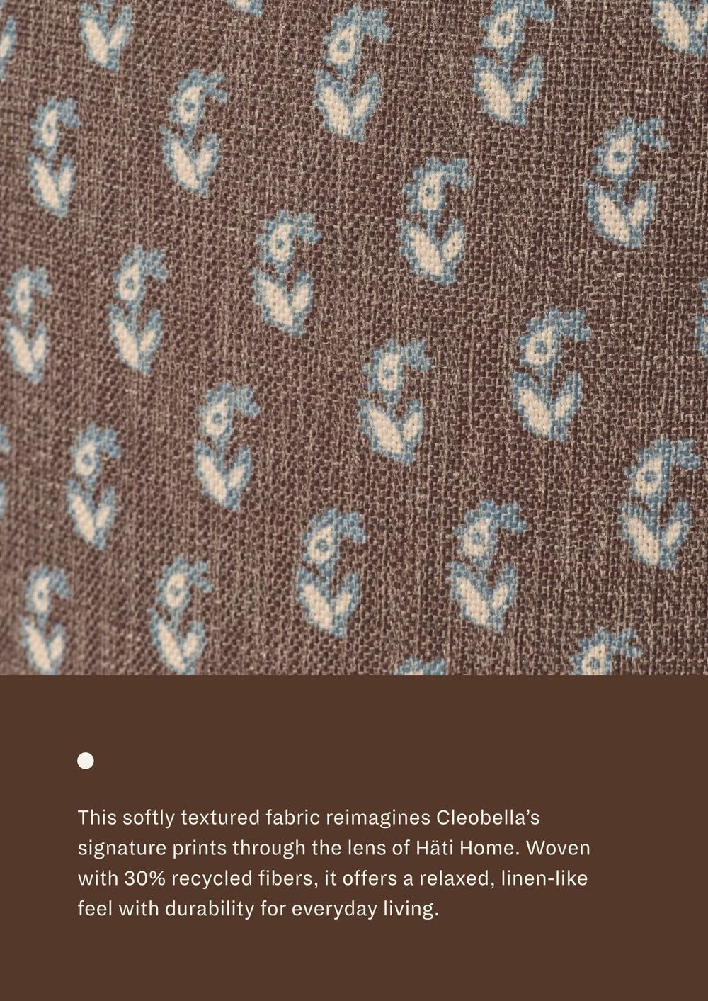 Close-up of floral brown fabric featuring a delicate floral motif in soft blue and ivory on a chocolate-brown background. Woven with recycled fibers, the textile offers a relaxed, linen-like texture designed for everyday durability.
