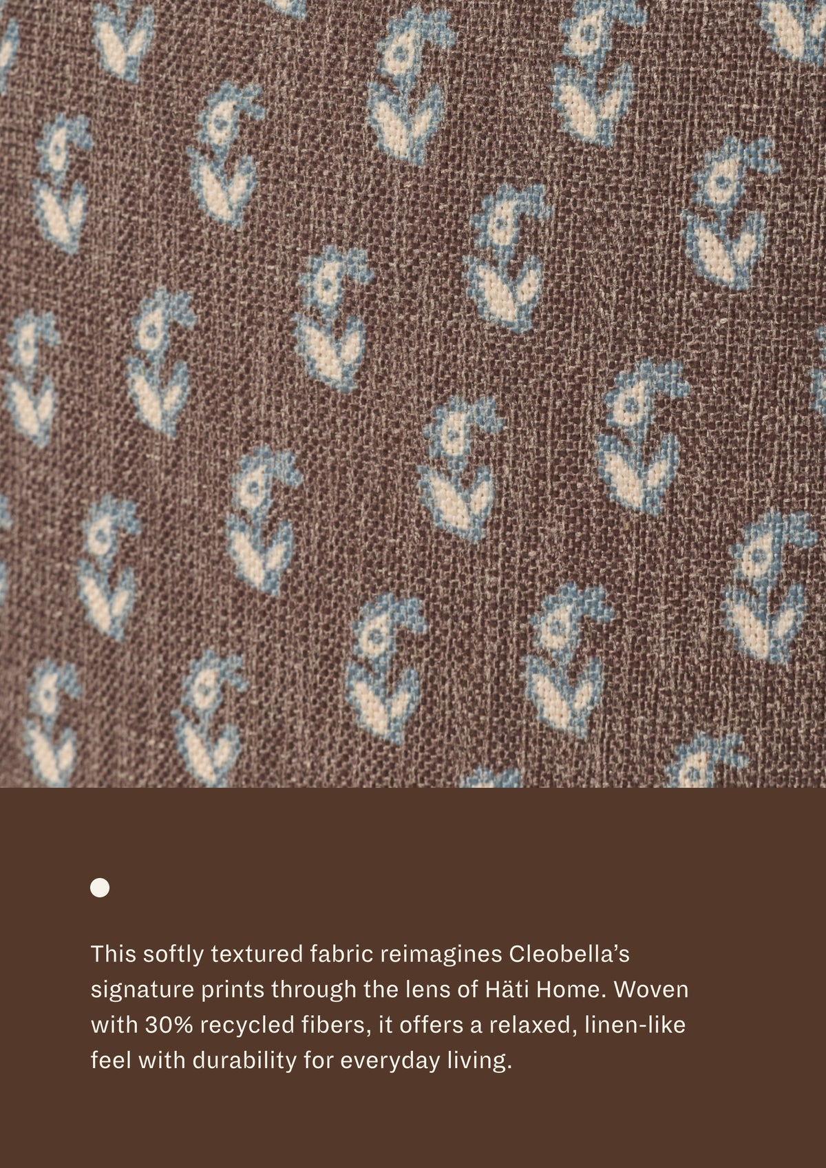 Close-up of floral brown fabric featuring a delicate floral motif in soft blue and ivory on a chocolate-brown background. Woven with recycled fibers, the textile offers a relaxed, linen-like texture designed for everyday durability.