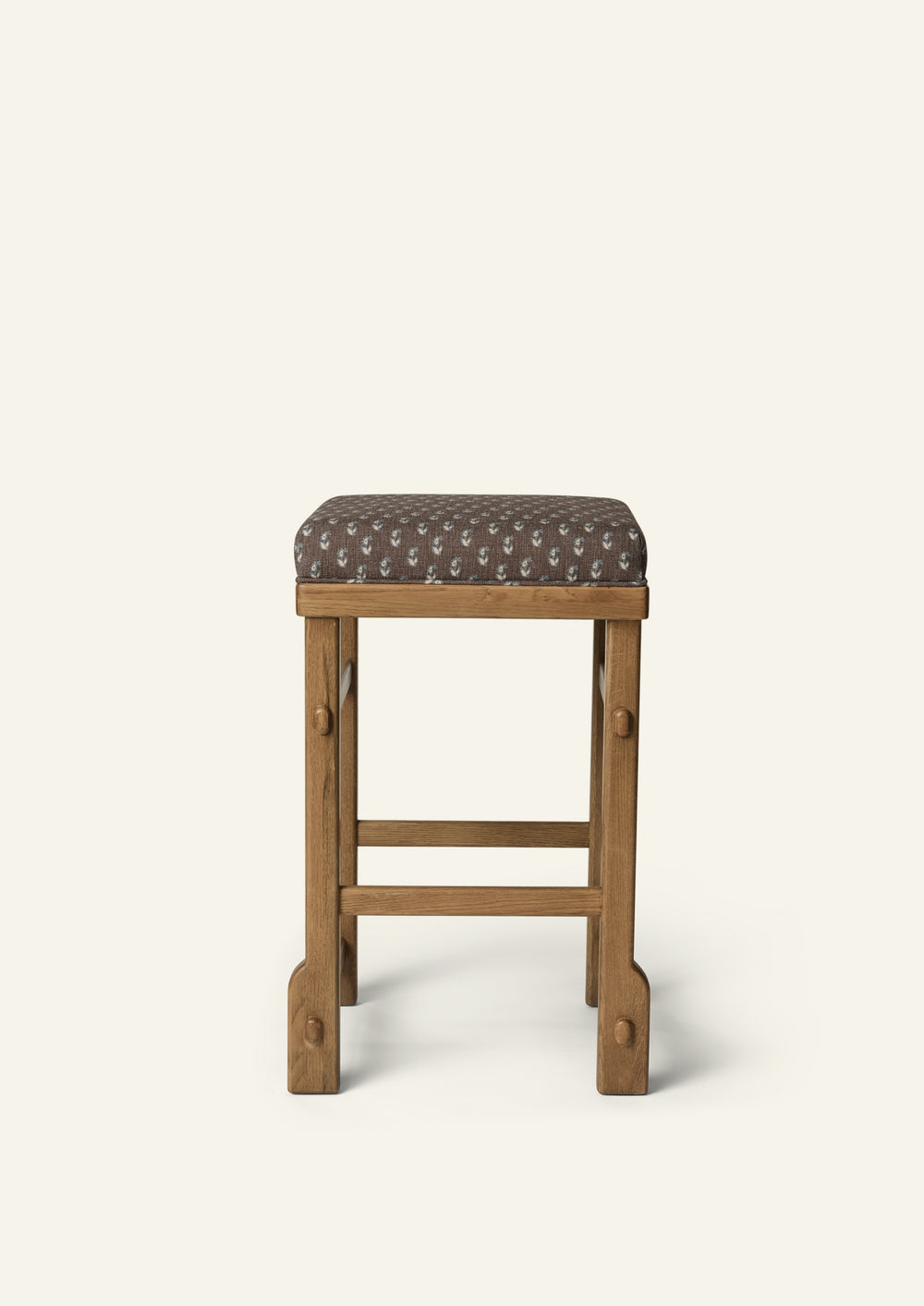 Side profile of the upholstered counter stool highlighting the Cocoa Floral cushion, solid honey oak frame, and exposed joinery details. The balanced proportions and handcrafted construction bring comfort and timeless appeal to kitchen and dining spaces.
