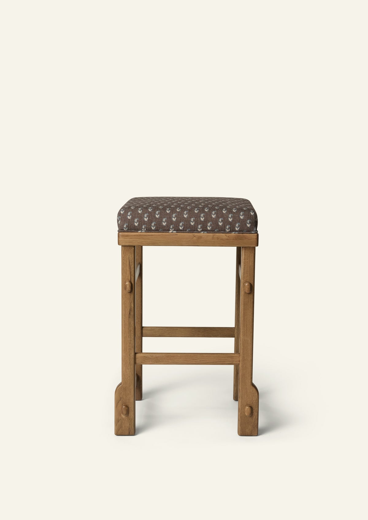 Side profile of the upholstered counter stool highlighting the Cocoa Floral cushion, solid honey oak frame, and exposed joinery details. The balanced proportions and handcrafted construction bring comfort and timeless appeal to kitchen and dining spaces.
