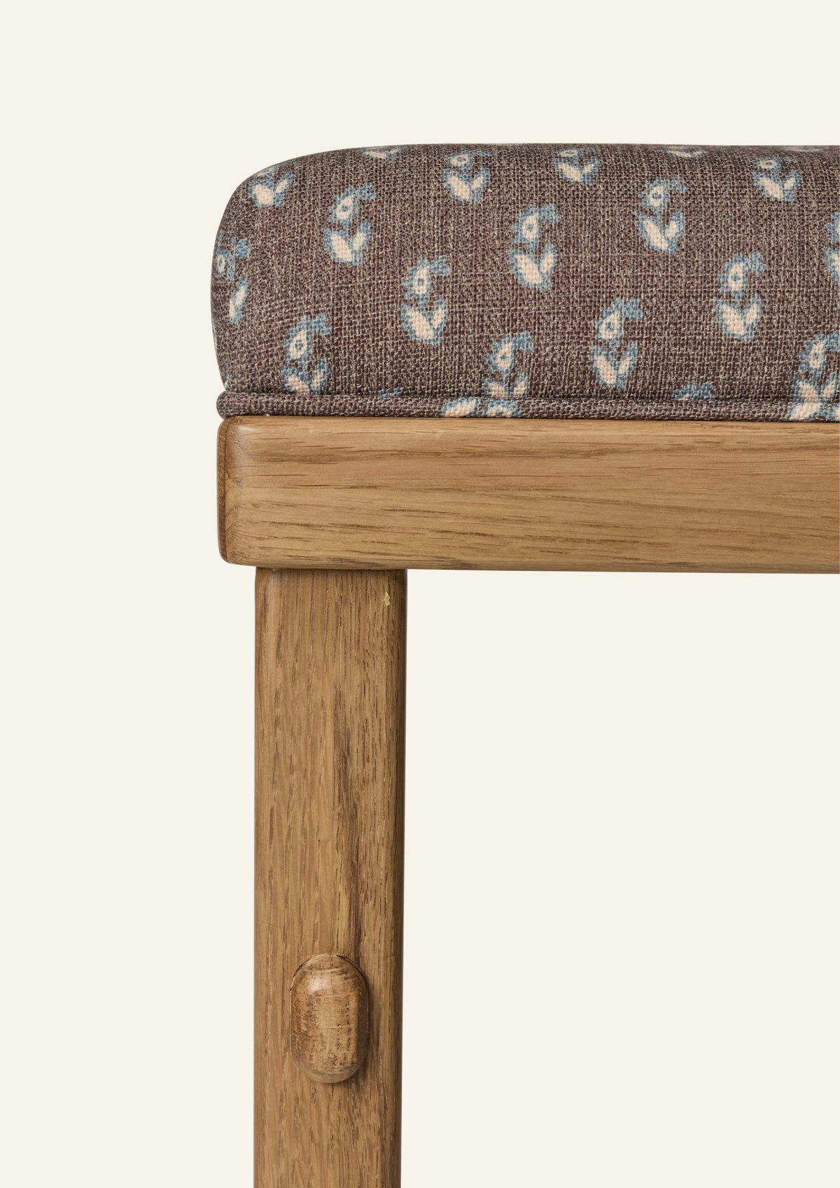 Close-up of the counter stool showcasing floral brown upholstery and a honey oak frame. The fabric features a small-scale floral print in soft blue and ivory against a rich brown ground.